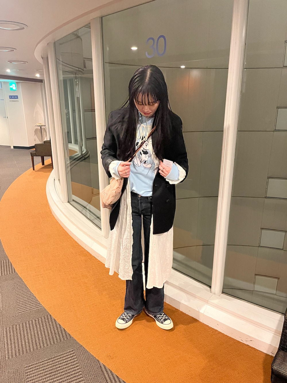 ブルー系のスウェット、ホワイト系のシャツワンピース、ブラック系のデニムパンツを着用したレディースの春コーディネートの3枚目の写真