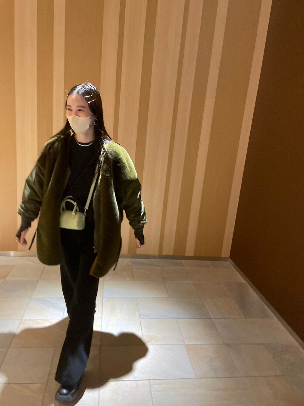 グリーン系のショルダーバッグ、ブラック系のブーツを着用したレディースの冬コーディネートの2枚目の写真