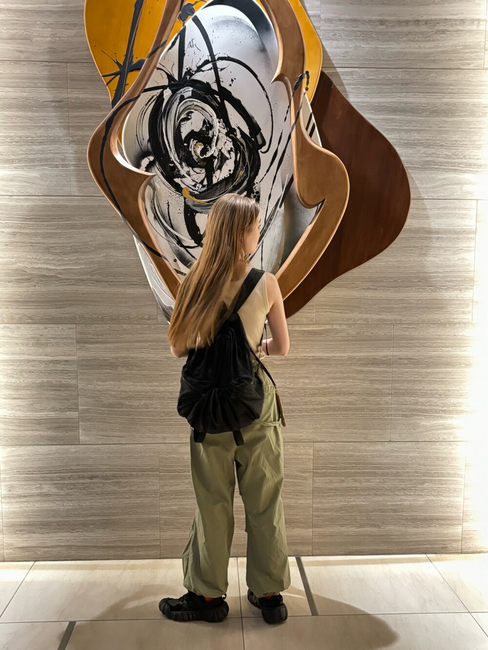 グリーン系のパンツ、イエロー系のタンクトップ、ブラック系のスニーカーを着用したレディースの夏コーディネートの2枚目の写真