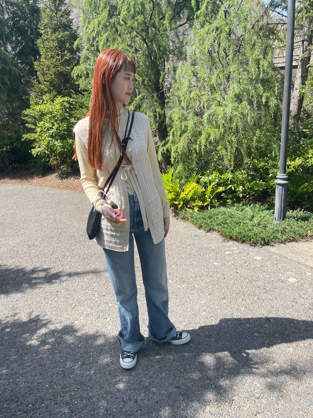 ブルー系のデニムパンツ、ベージュ系のベスト、ブラック系のスニーカーを着用したレディースの春コーディネートの2枚目の写真