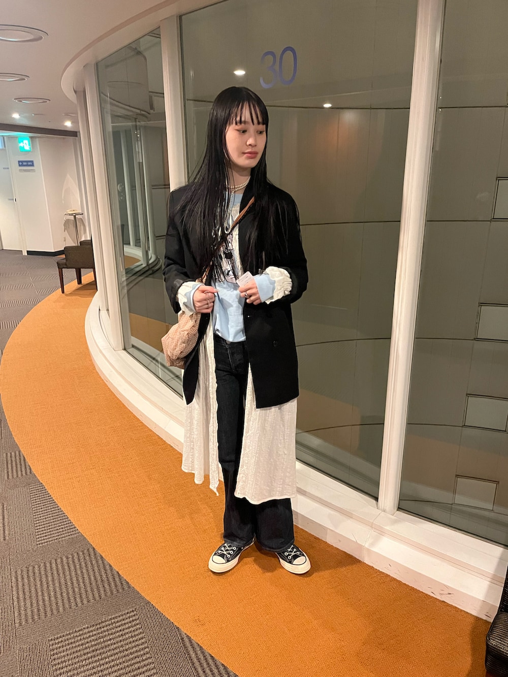 ブルー系のスウェット、ホワイト系のシャツワンピース、ブラック系のデニムパンツを着用したレディースの春コーディネートの2枚目の写真