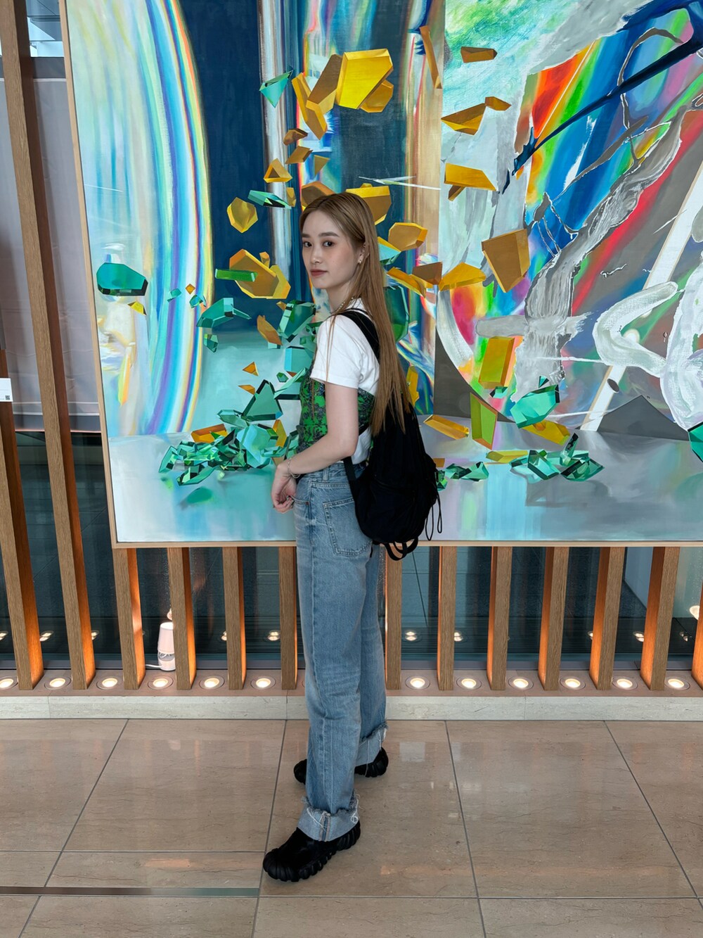 ブルー系のデニムパンツ、ブラック系のスニーカー、ホワイト系のTシャツ/カットソーを着用したレディースの夏コーディネートの2枚目の写真