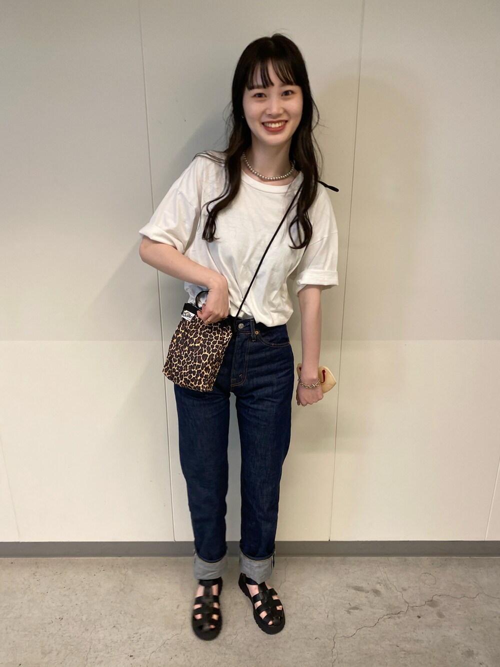 ブラウン系のショルダーバッグ、ブラック系のサンダル、ホワイト系のTシャツ/カットソーを着用したレディースの春コーディネートの2枚目の写真