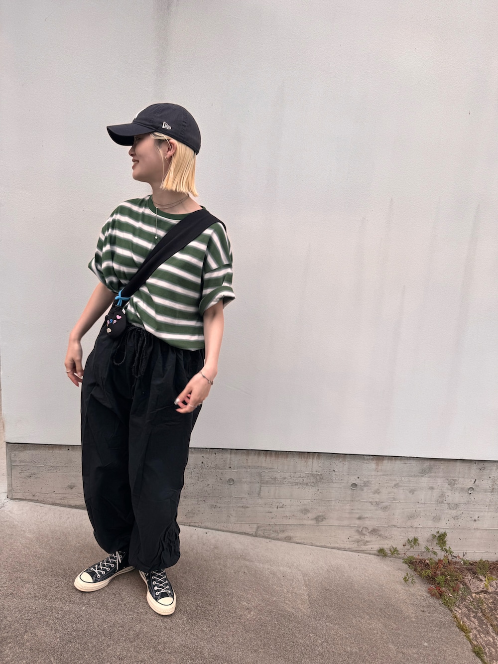 グリーン系のTシャツ/カットソー、ブラック系のショルダーバッグ、ブラック系のパンツを着用したレディースの夏コーディネートの2枚目の写真
