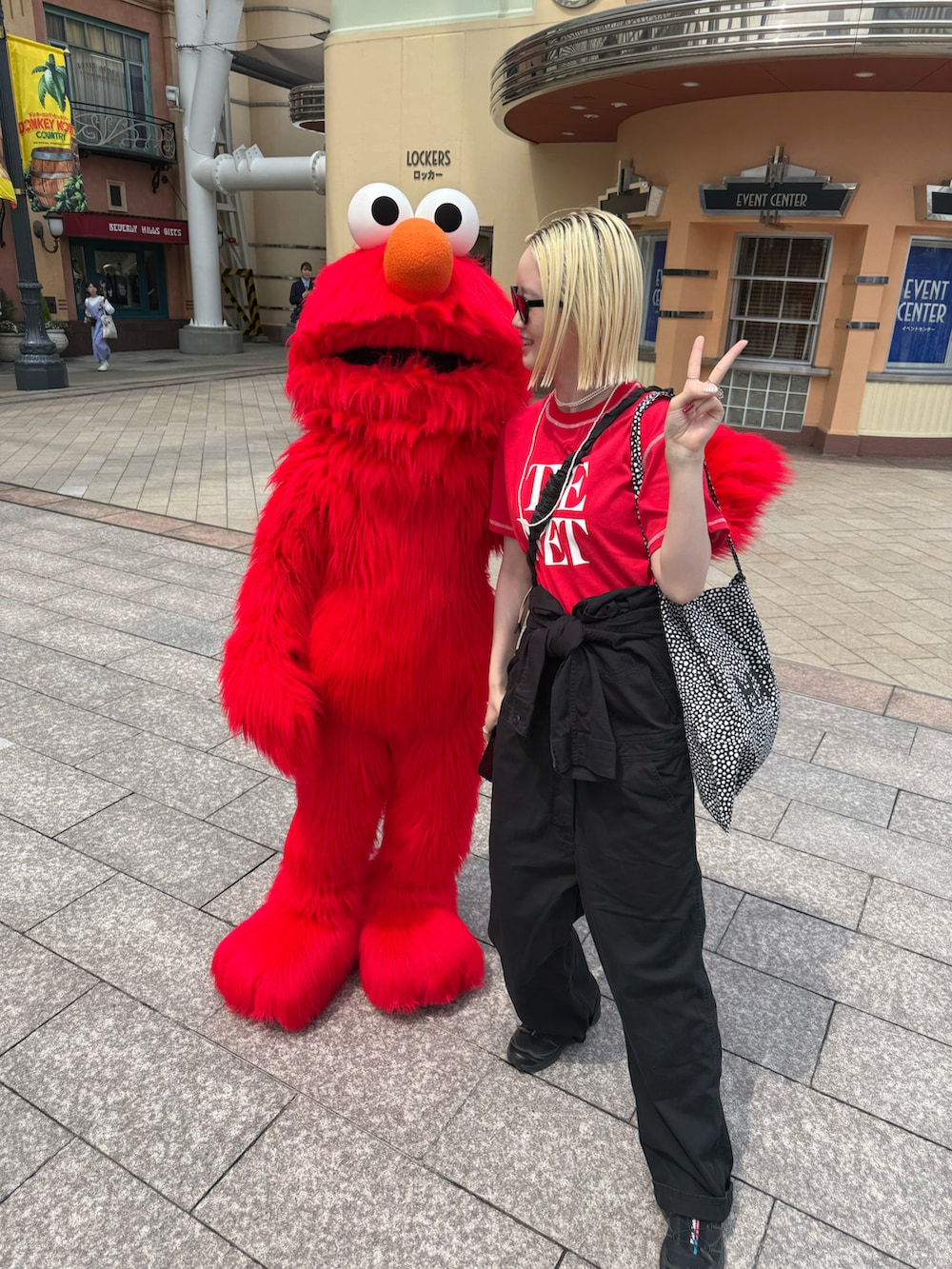 レッド系のTシャツ/カットソー、ブラック系のつなぎ/オールインワン、ブラック系のスニーカーを着用したレディースの夏コーディネートの2枚目の写真