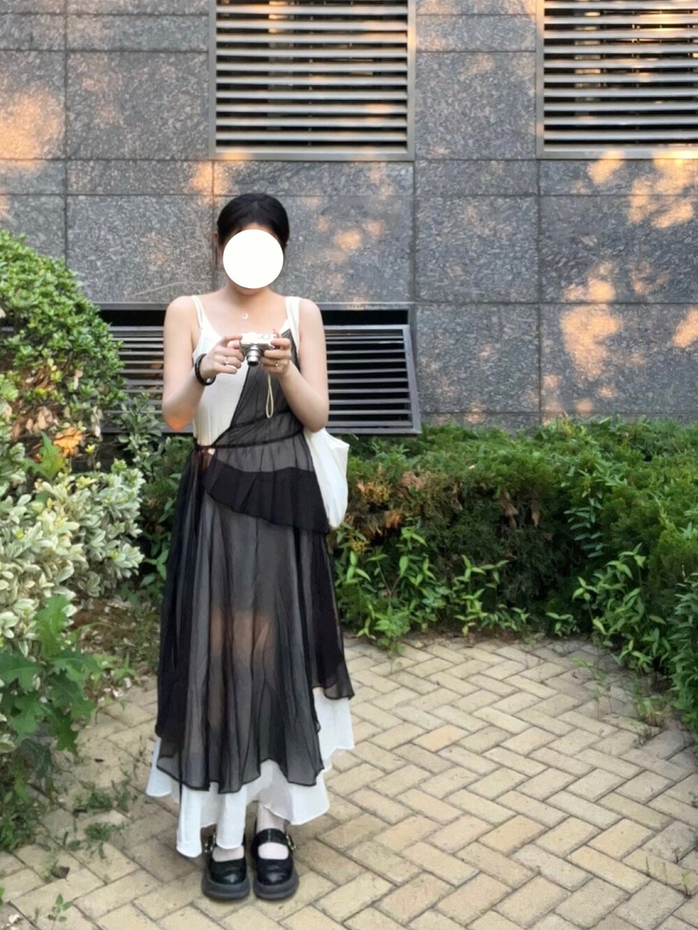 ブラック系のワンピース、ブラック系のシューズ、ホワイト系のショルダーバッグを着用したレディースの夏コーディネートの2枚目の写真