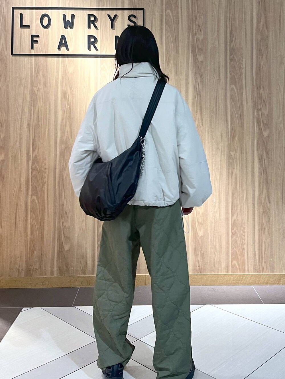 グリーン系のその他パンツ、ホワイト系のその他アウター、ブラック系のショルダーバッグを着用したレディースの冬コーディネートの2枚目の写真
