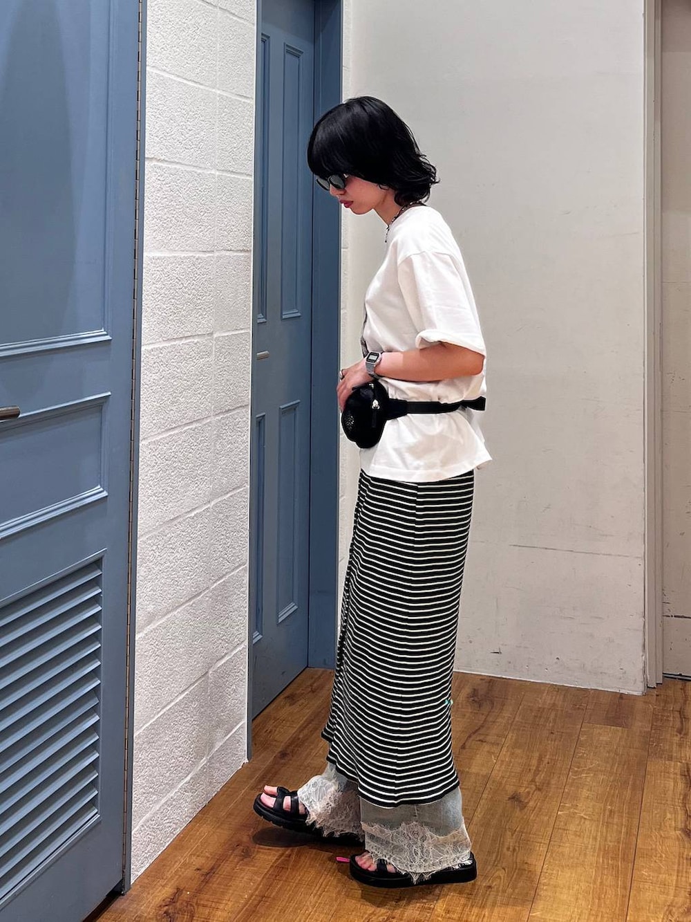 ブルー系のデニムパンツ、ブラック系のボディバッグ/ウエストポーチ、ブラック系のサンダルを着用したレディースの夏コーディネートの2枚目の写真