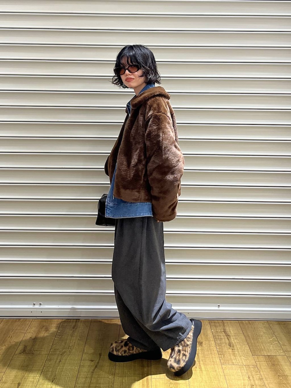 ブラウン系のブルゾン、ブルー系のデニムジャケット、ブラック系のボストンバッグを着用したレディースの秋コーディネートの2枚目の写真