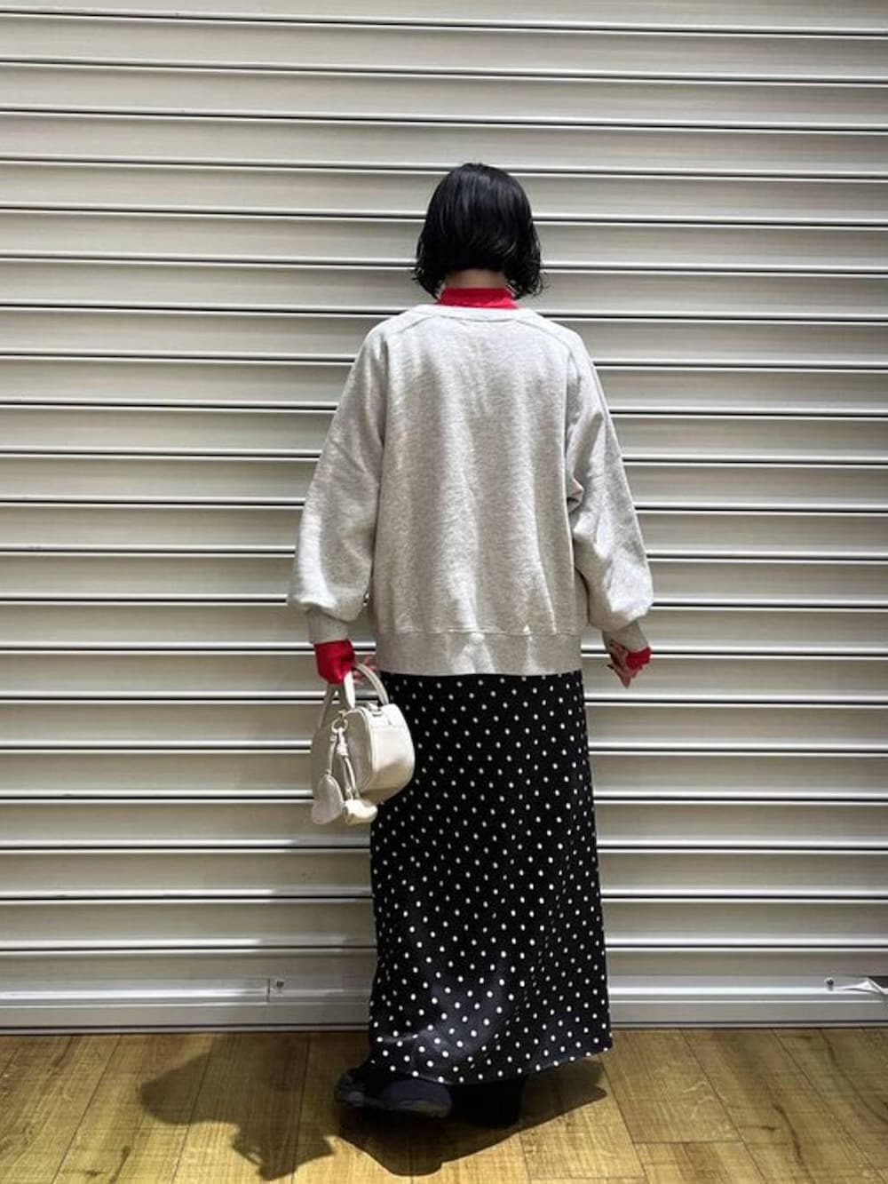 ホワイト系のスカート、レッド系のニット/セーター、ブラック系のその他パンツを着用したレディースの冬コーディネートの3枚目の写真