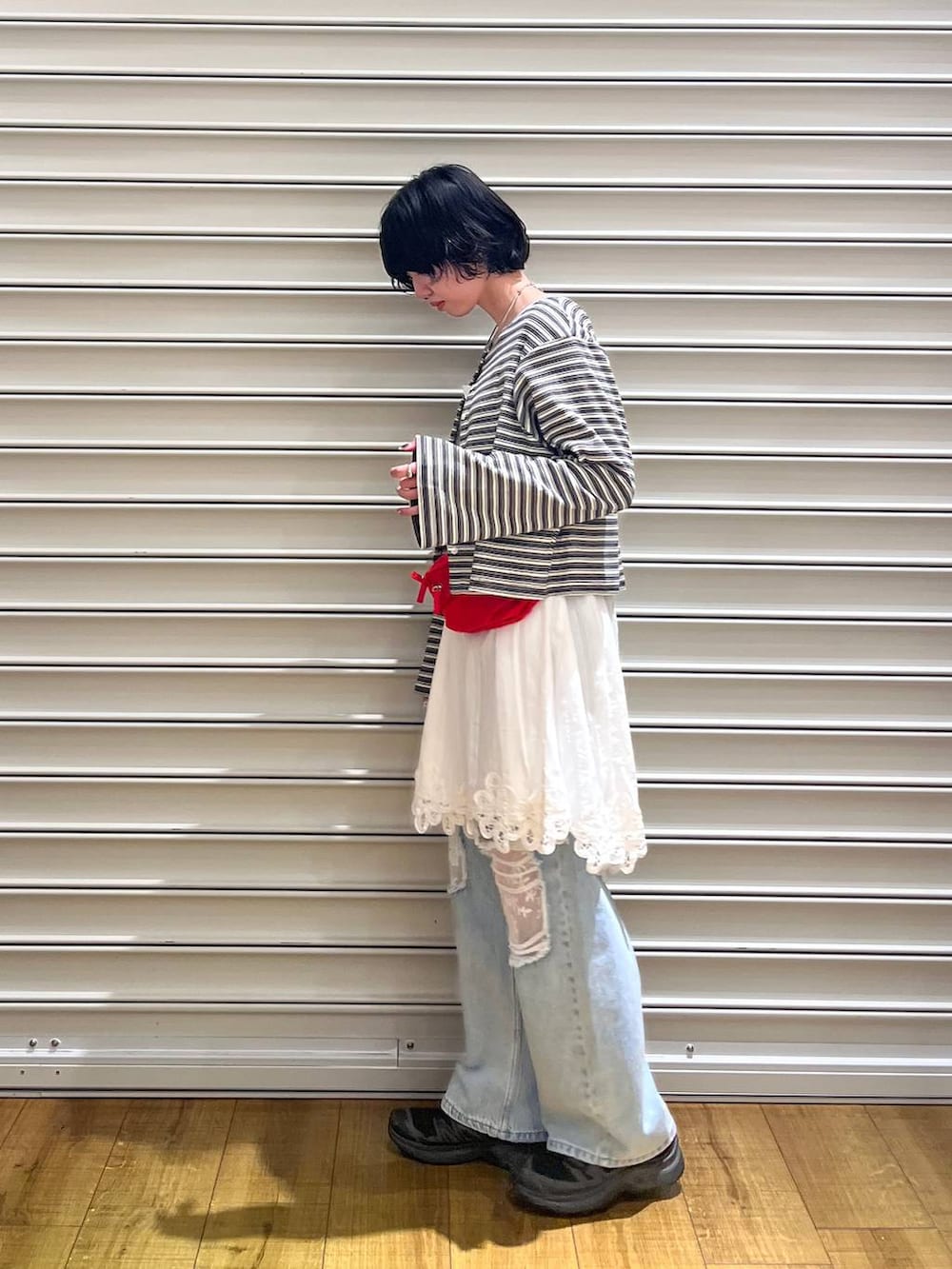 ブルー系のデニムパンツ、レッド系のボディバッグ/ウエストポーチ、ホワイト系のワンピースを着用したレディースの春コーディネートの2枚目の写真