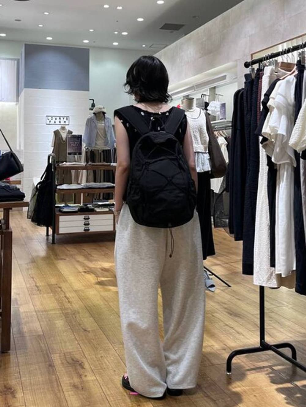 グレー系のスウェットパンツ、ブラウン系のサンダル、ブラック系のバックパック/リュックを着用したレディースの夏コーディネートの3枚目の写真