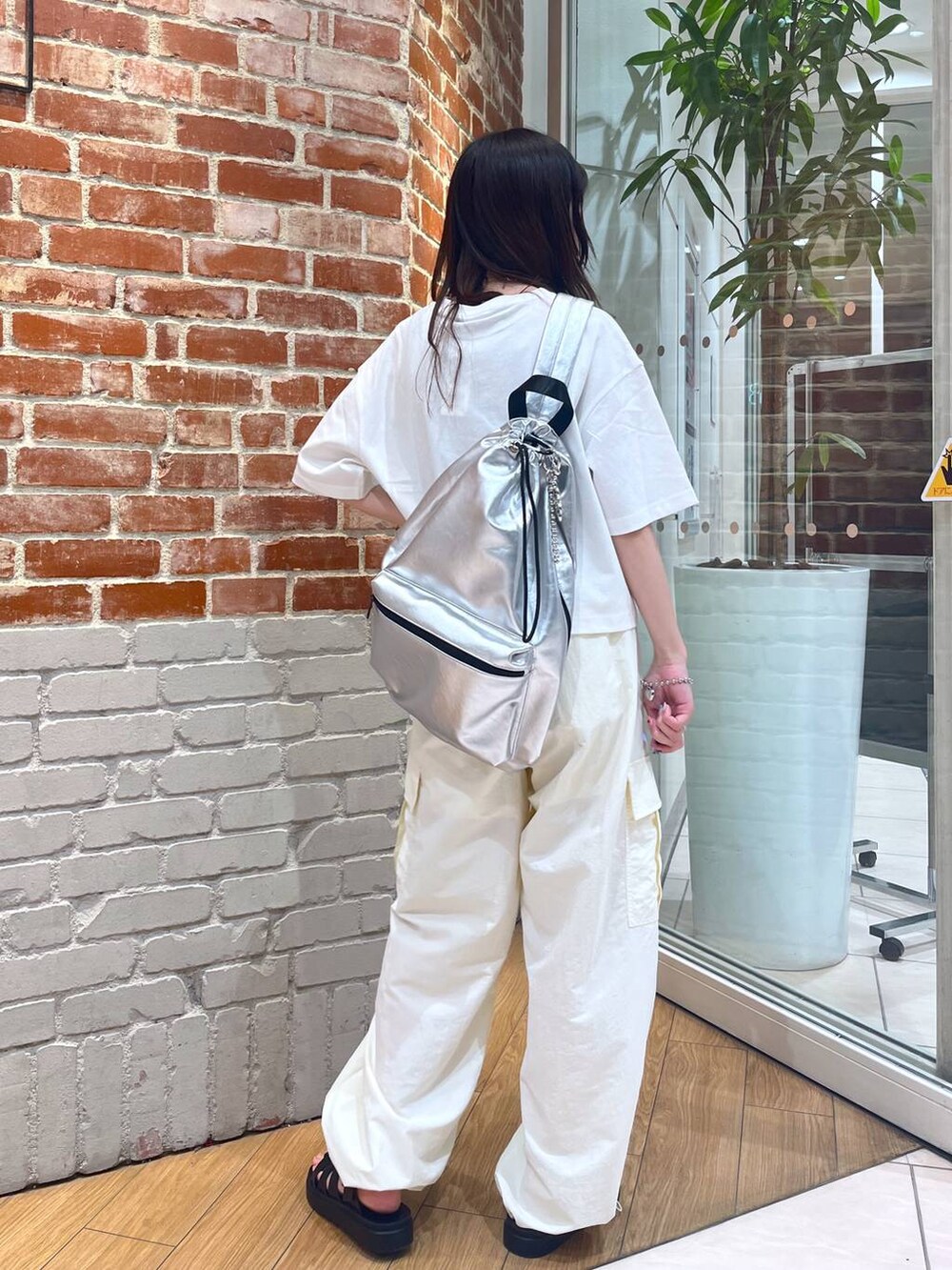 ホワイト系のTシャツ/カットソー、シルバー系のショルダーバッグ、ブラック系のスニーカーを着用したレディースの夏コーディネートの2枚目の写真