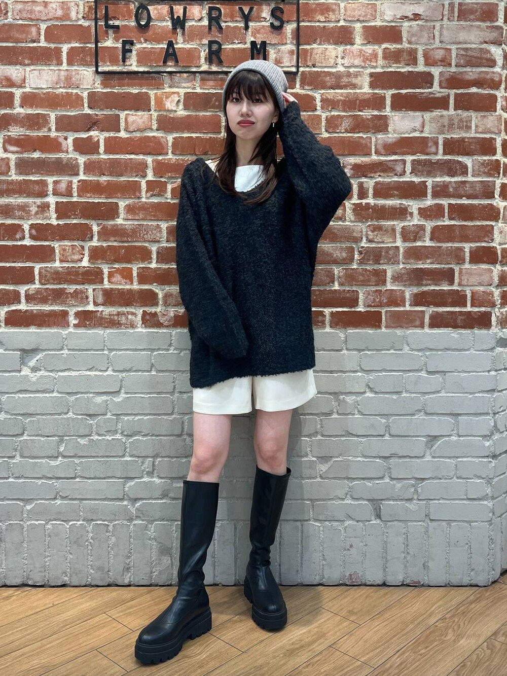 ブラック系のニット/セーター、ホワイト系のTシャツ/カットソー、ブラック系のブーツを着用したレディースの冬コーディネートの2枚目の写真