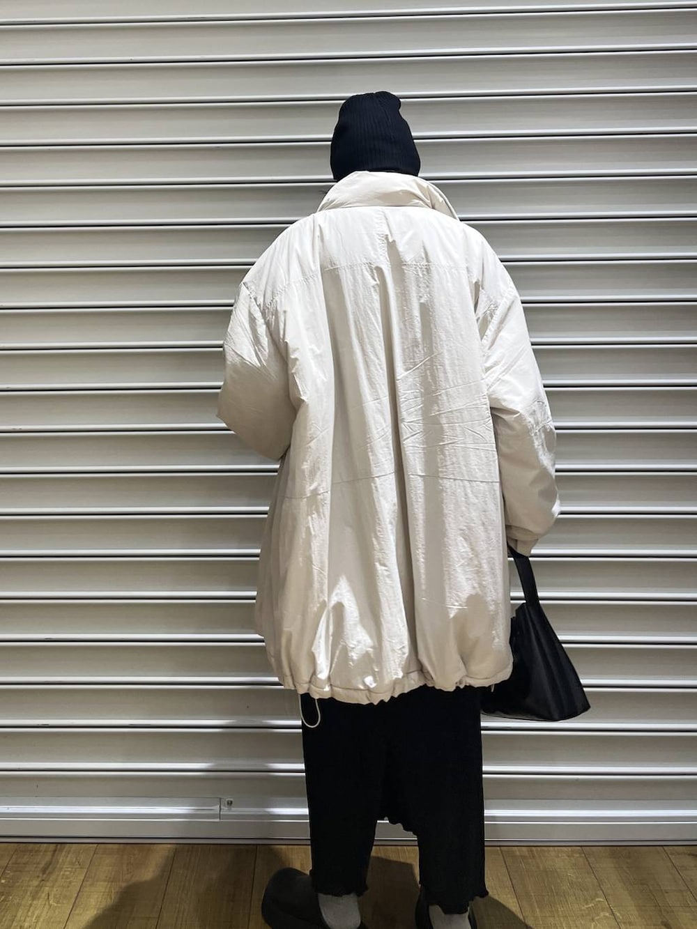 ホワイト系のブルゾン、ブラック系のサンダル、ブラック系のスカートを着用したレディースの冬コーディネートの3枚目の写真