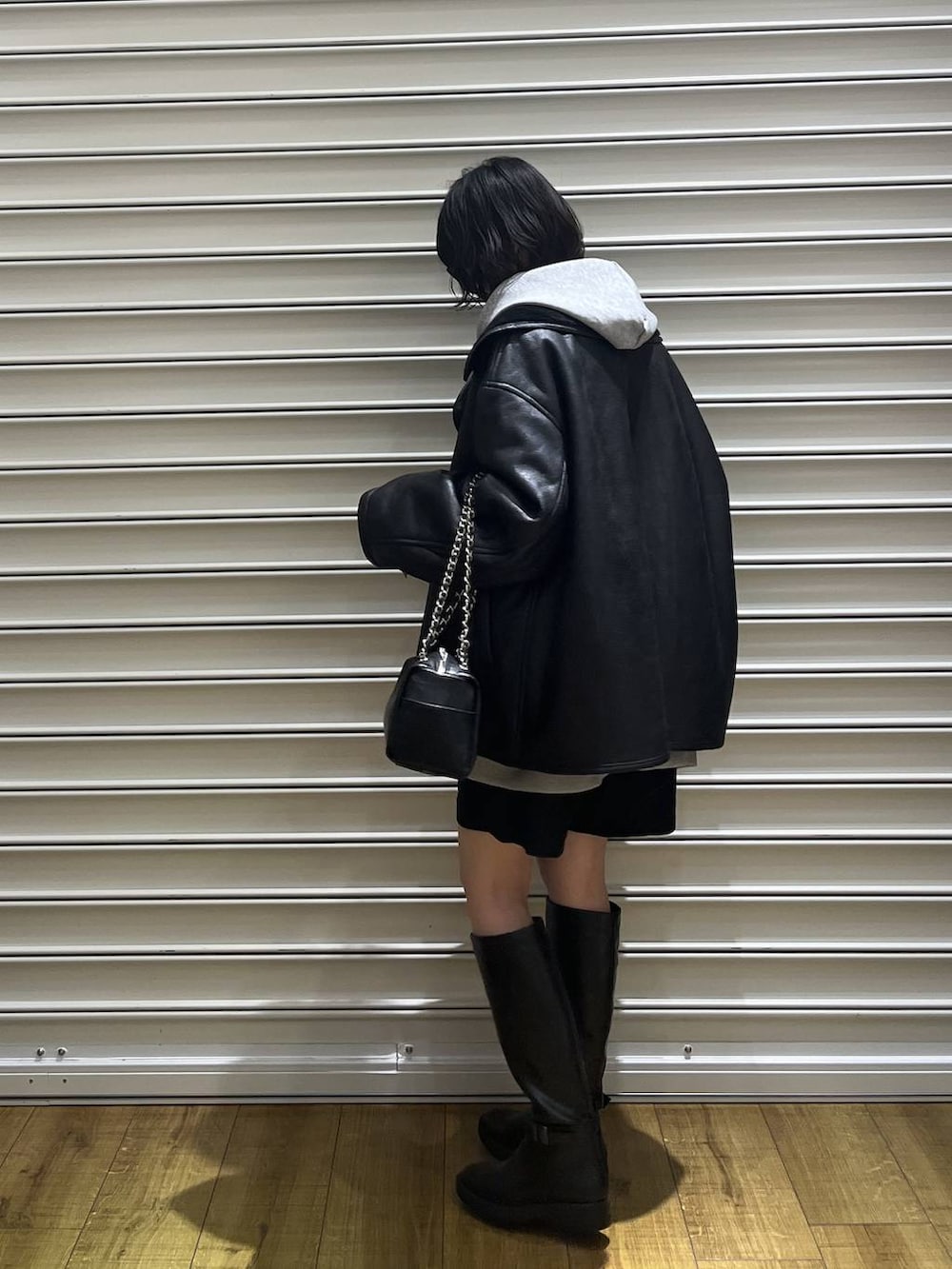 グレー系のパーカー、ブラック系のムートンコート、ブラック系のその他パンツを着用したレディースの冬コーディネートの3枚目の写真