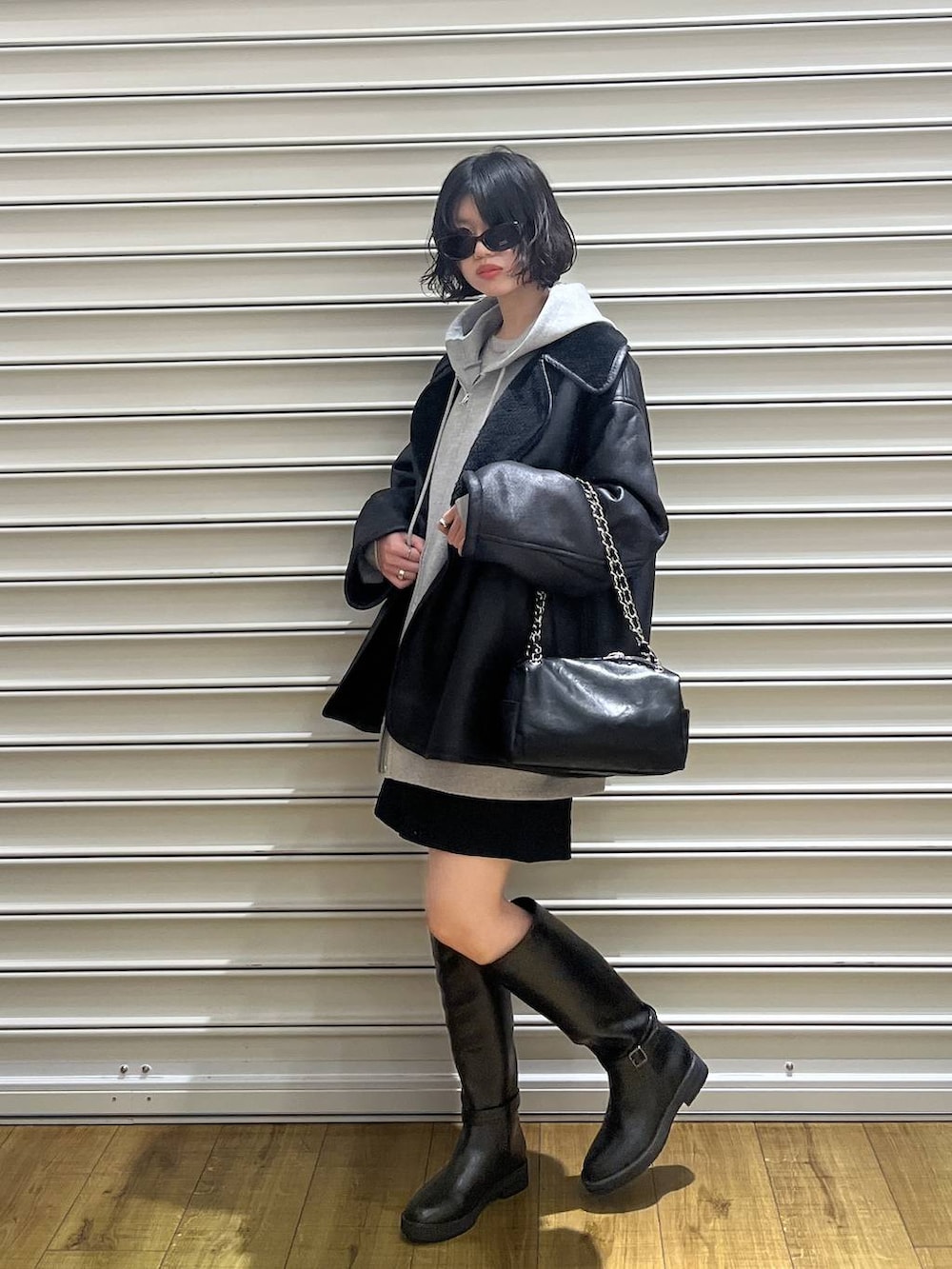 グレー系のパーカー、ブラック系のムートンコート、ブラック系のその他パンツを着用したレディースの冬コーディネートの2枚目の写真