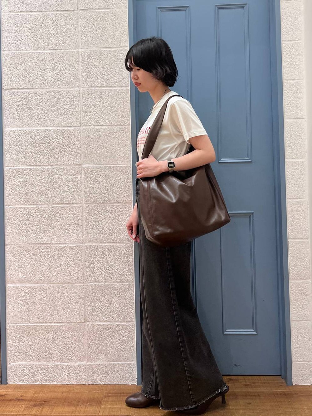 ブラウン系のショルダーバッグ、ブラック系のデニムパンツ、ブラウン系のサンダルを着用したレディースの春コーディネートの2枚目の写真