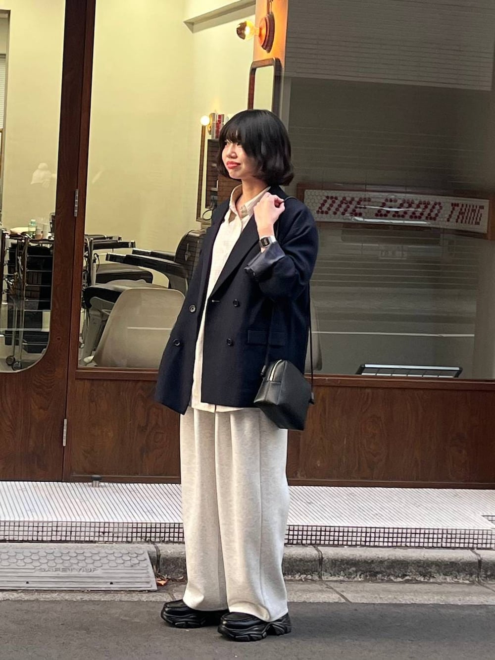 グレー系のスウェットパンツ、ブルー系のテーラードジャケット、ブラック系のローファーを着用したレディースの冬コーディネートの2枚目の写真