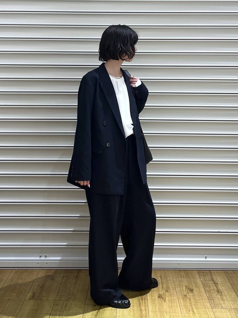 ブラック系のショルダーバッグ、ブルー系のテーラードジャケット、ホワイト系のシャツ/ブラウスを着用したレディースの冬コーディネートの2枚目の写真