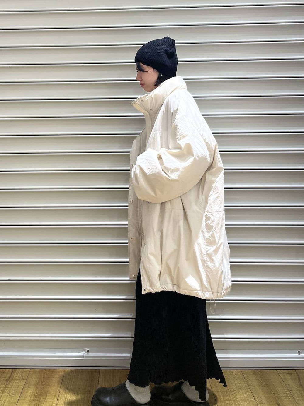 ホワイト系のブルゾン、ブラック系のサンダル、ブラック系のスカートを着用したレディースの冬コーディネートの2枚目の写真