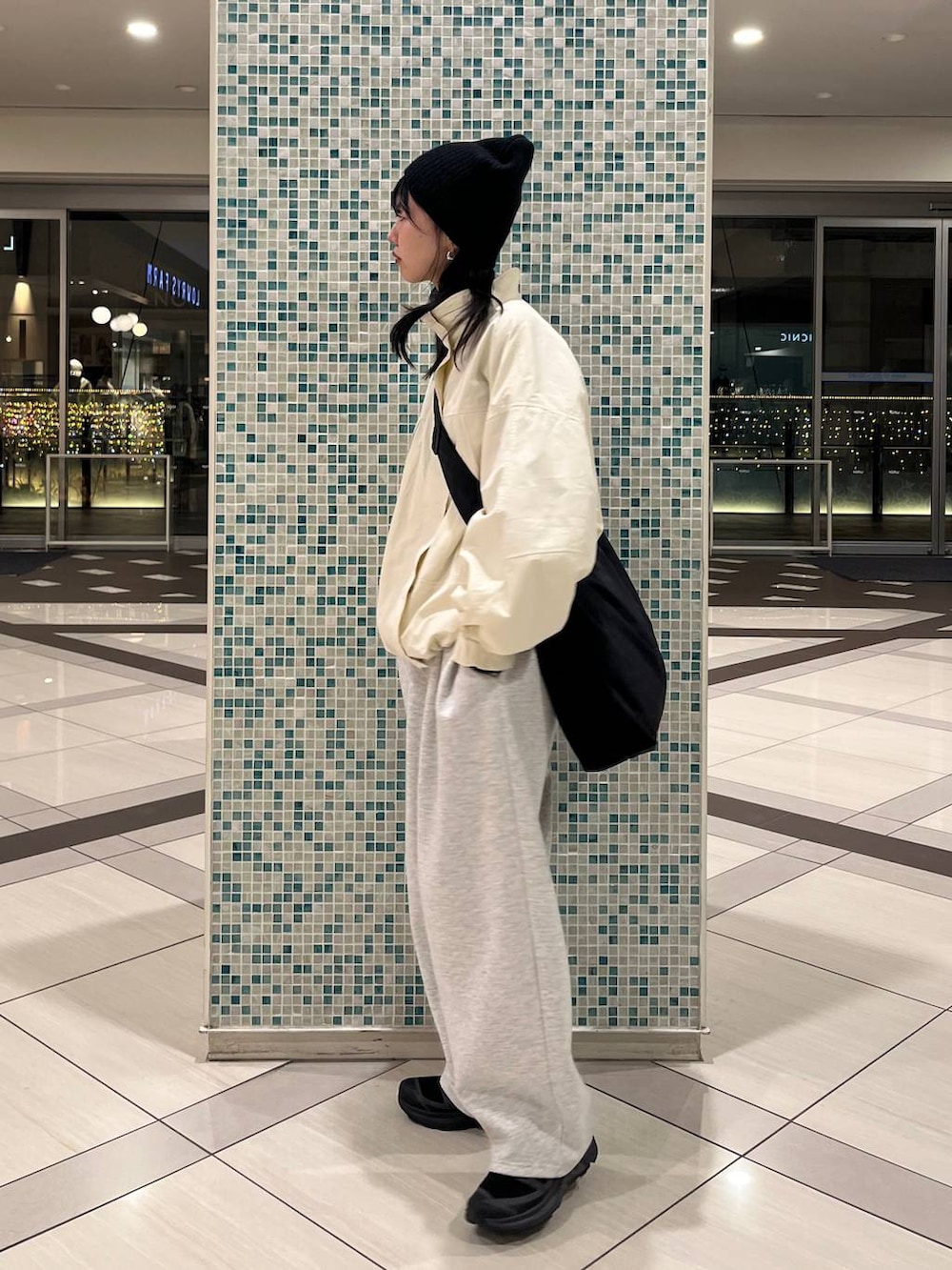 ブラウン系のショルダーバッグ、グレー系のスウェットパンツ、ホワイト系のナイロンジャケットを着用したレディースの冬コーディネートの2枚目の写真