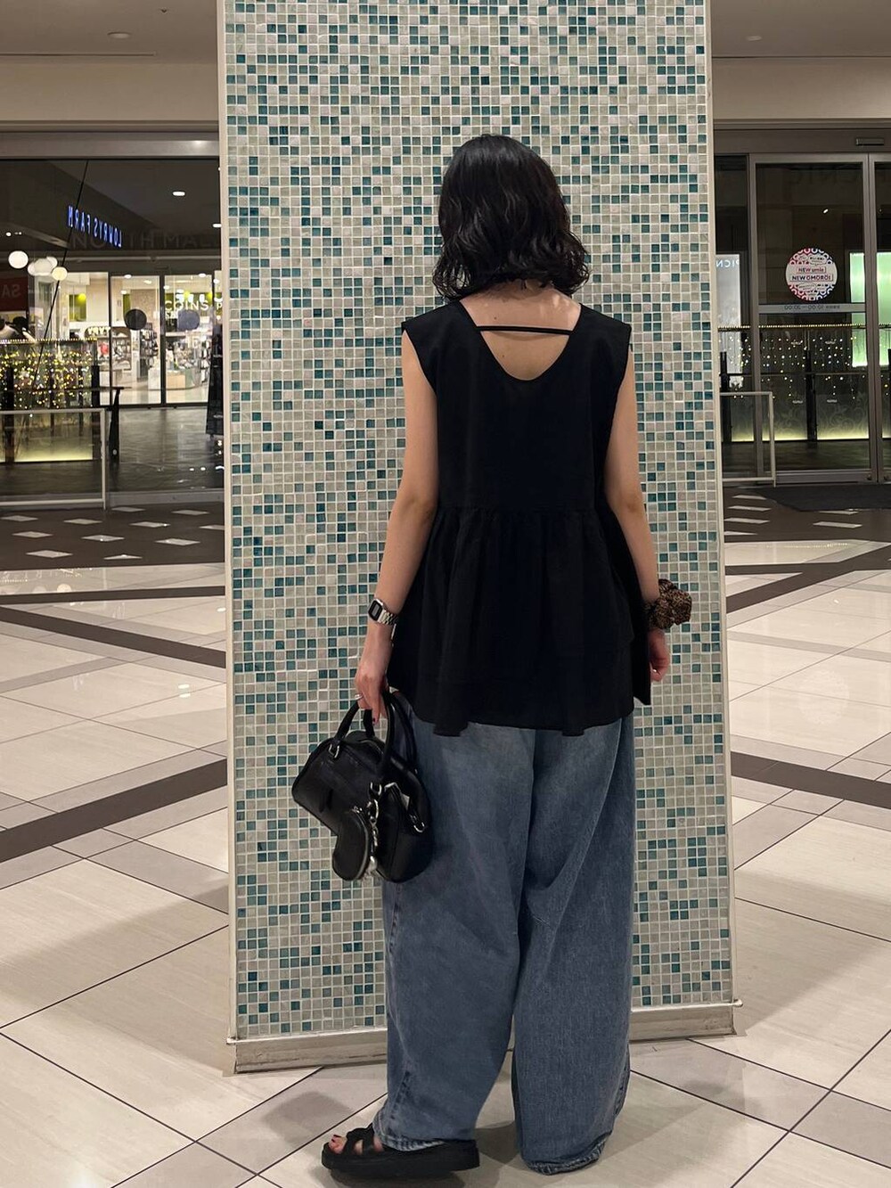 ブラック系のサンダル、ブルー系のデニムパンツ、ブラック系のショルダーバッグを着用したレディースの夏コーディネートの3枚目の写真