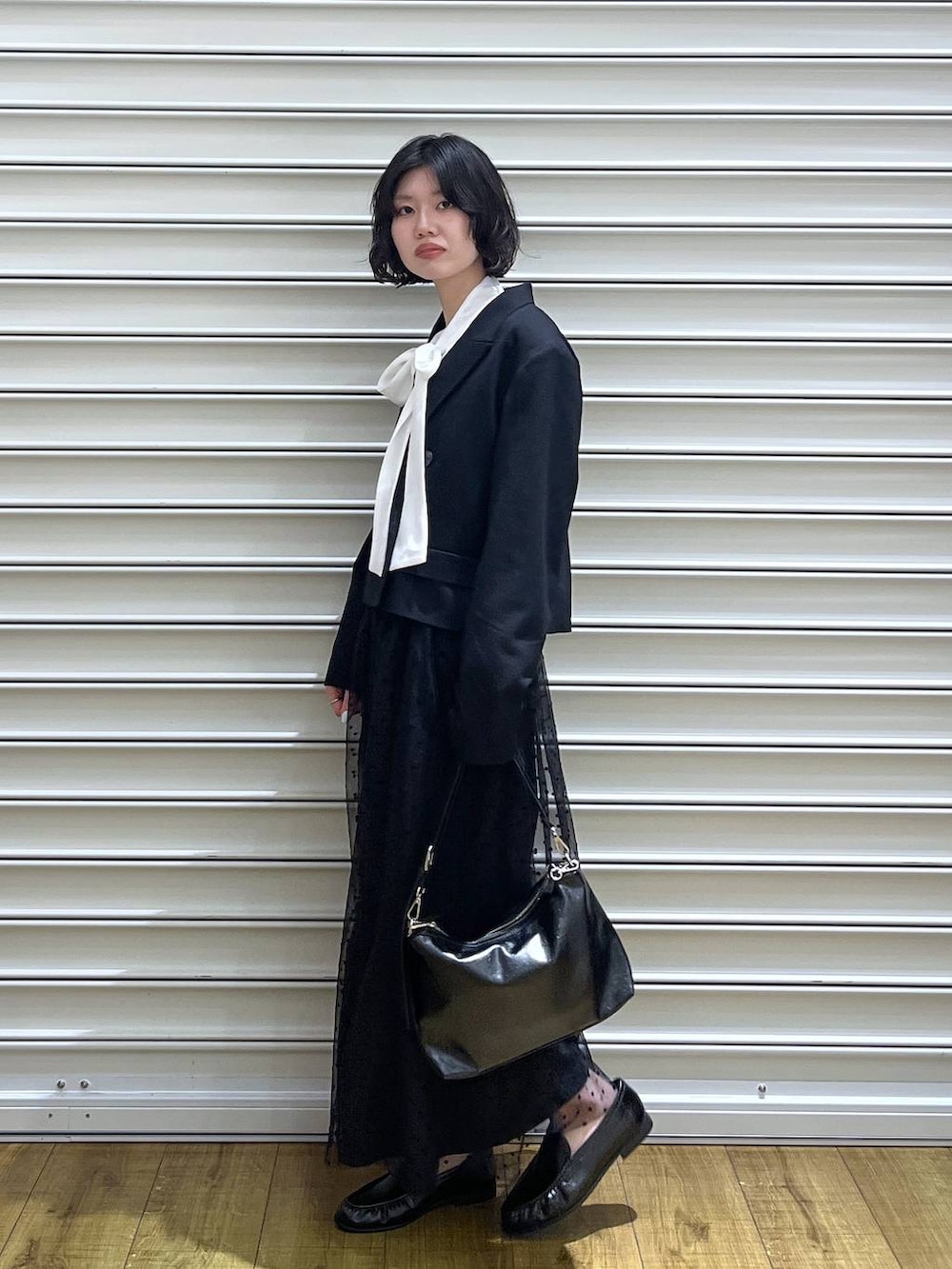 ブラック系のテーラードジャケット、ホワイト系のシャツ/ブラウス、ブラック系のスカートを着用したレディースの冬コーディネートの3枚目の写真