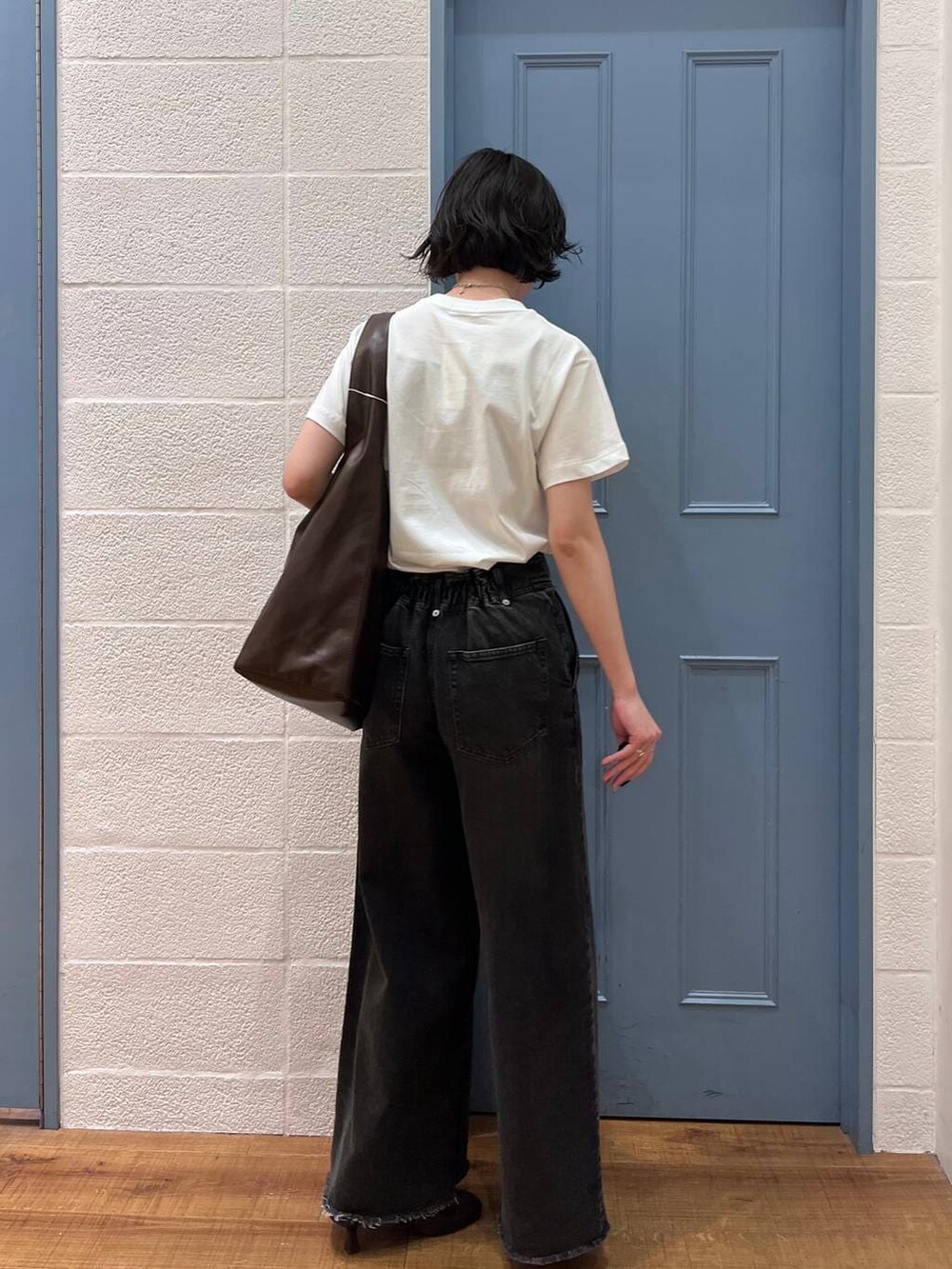 ブラウン系のショルダーバッグ、ブラック系のデニムパンツ、ブラウン系のサンダルを着用したレディースの春コーディネートの3枚目の写真