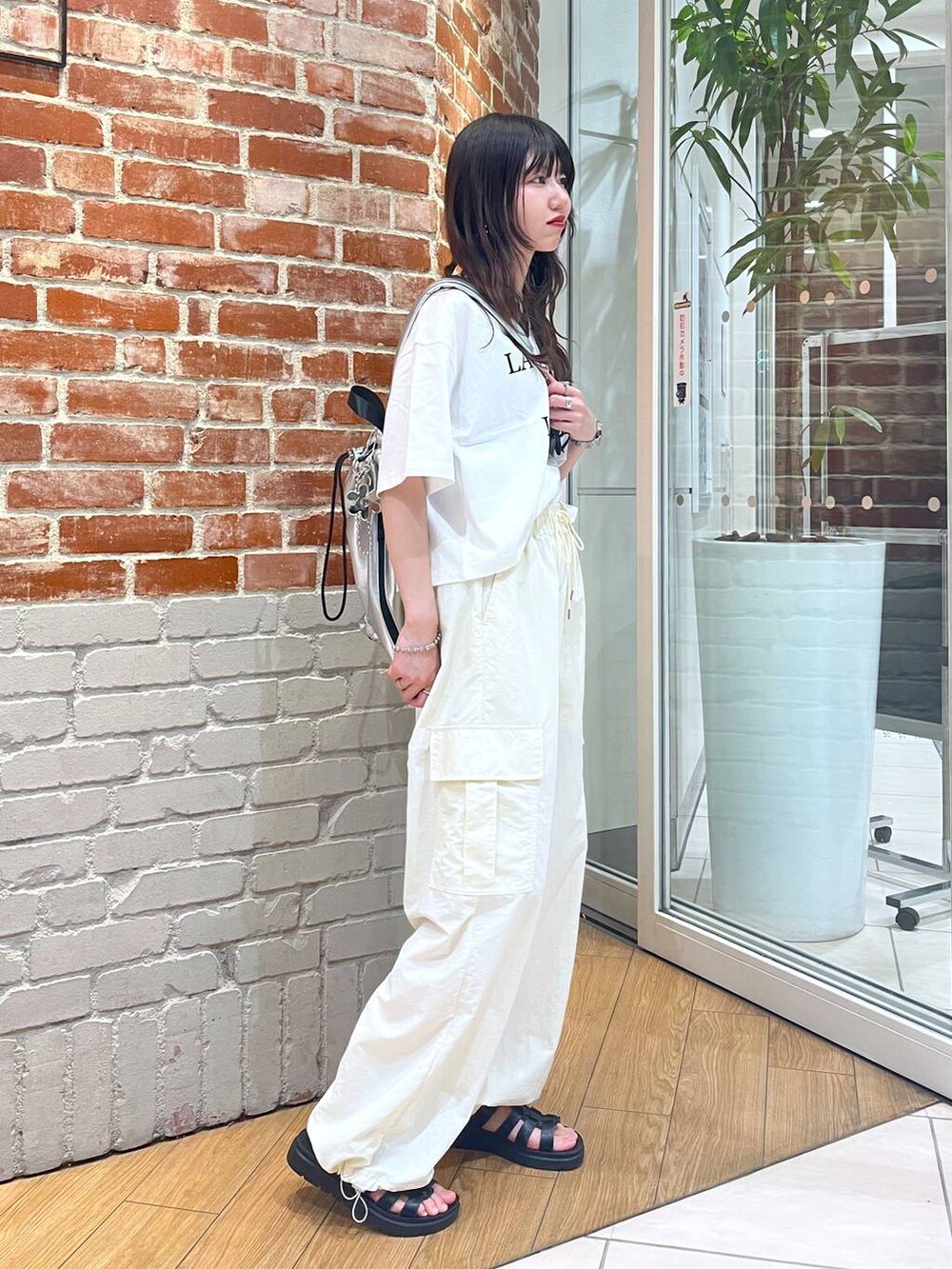 ホワイト系のTシャツ/カットソー、シルバー系のショルダーバッグ、ブラック系のスニーカーを着用したレディースの夏コーディネートの3枚目の写真