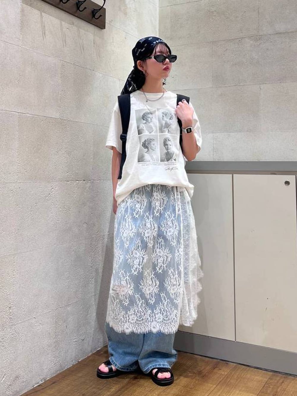 ブルー系のデニムパンツ、ブラック系のサンダル、ホワイト系のTシャツ/カットソーを着用したレディースの夏コーディネートの2枚目の写真