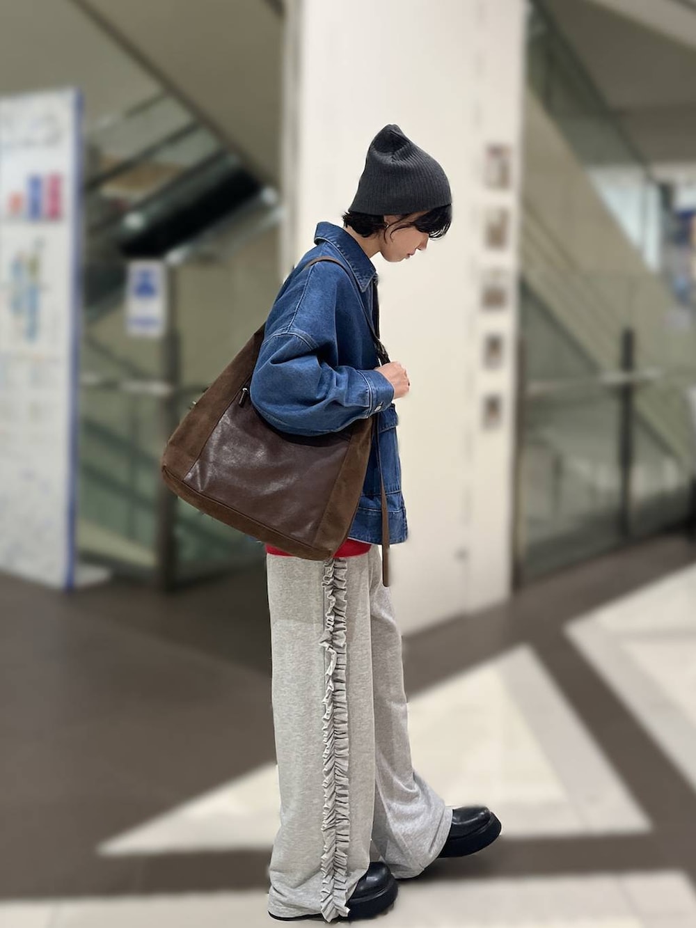 ブラウン系のショルダーバッグ、ブルー系のデニムジャケット、ブラック系のサンダルを着用したレディースの秋コーディネートの2枚目の写真