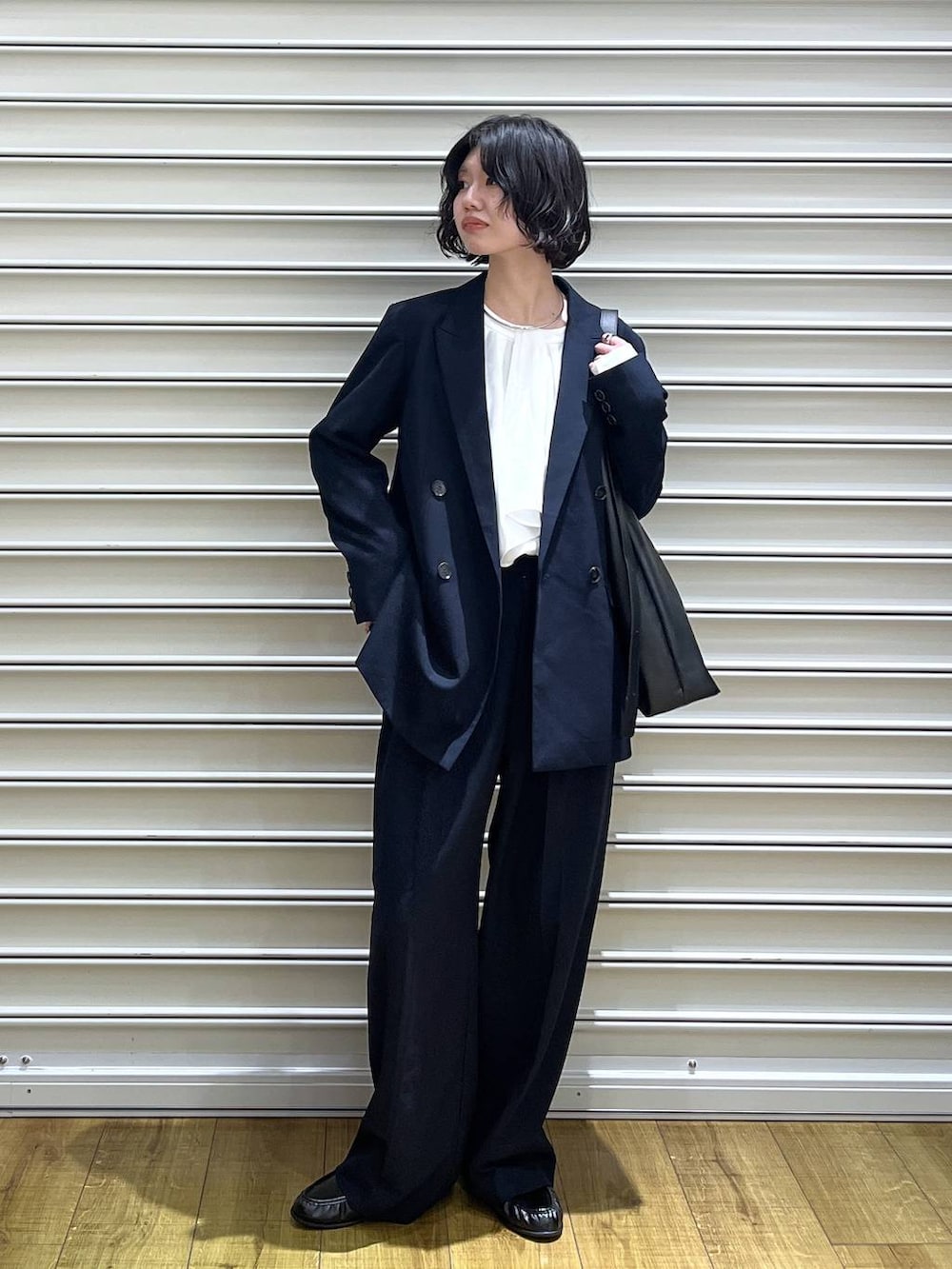 ブラック系のショルダーバッグ、ブルー系のテーラードジャケット、ホワイト系のシャツ/ブラウスを着用したレディースの冬コーディネートの3枚目の写真