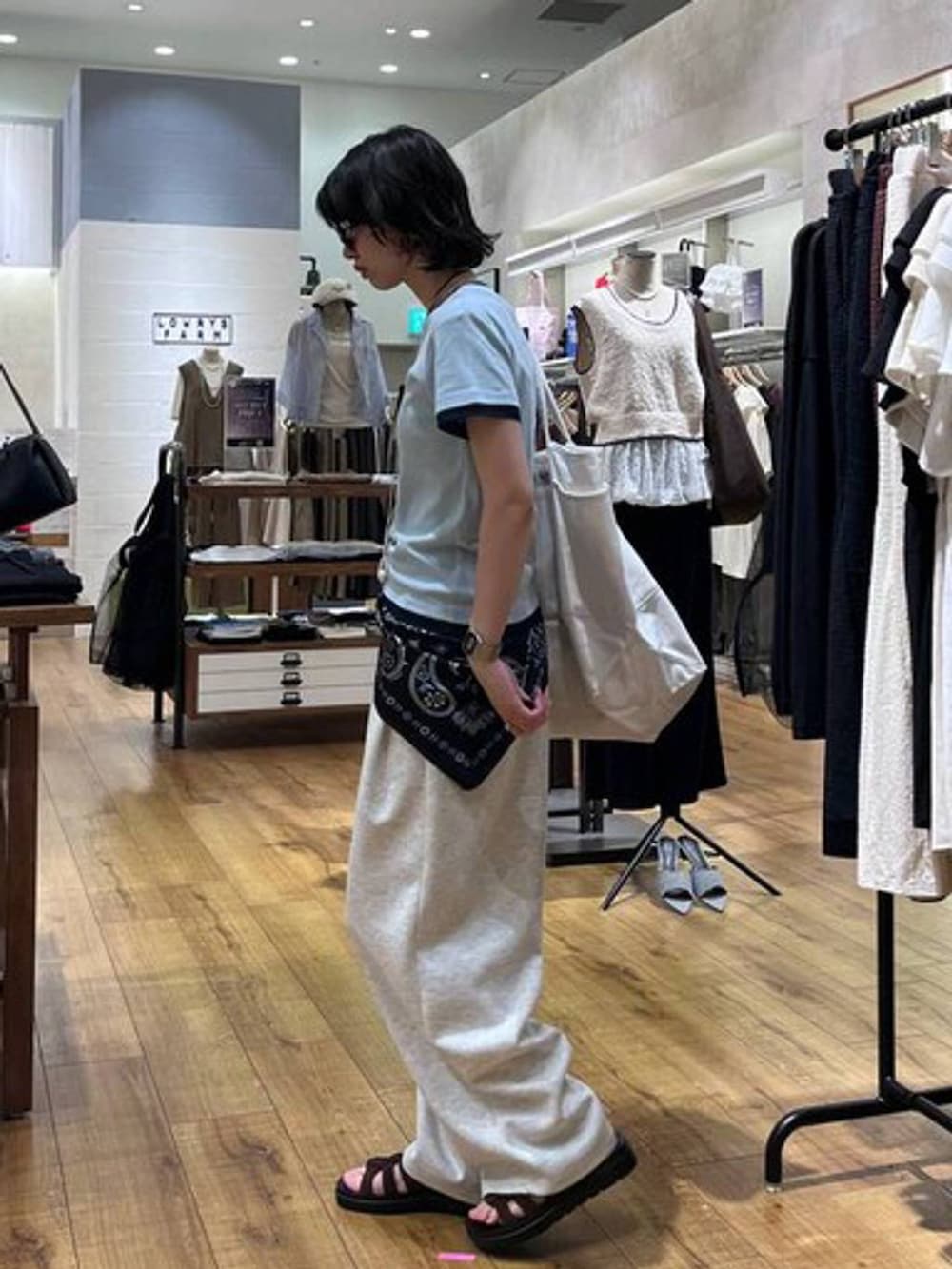 グレー系のスウェットパンツ、ブラウン系のサンダル、ホワイト系のトートバッグを着用したレディースの夏コーディネートの2枚目の写真