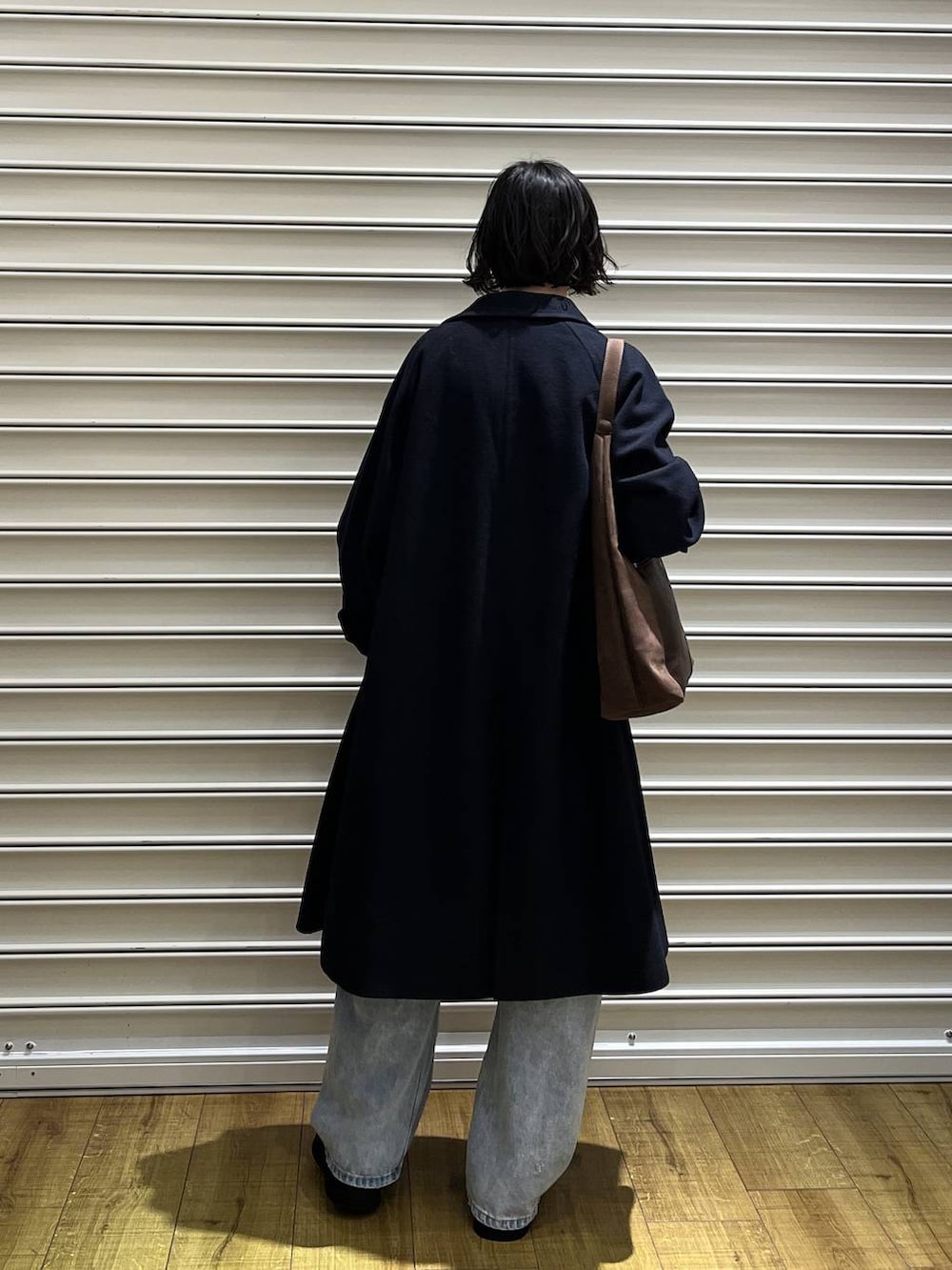 ブラウン系のショルダーバッグ、ブルー系のチェスターコート、ブラック系のサンダルを着用したレディースの冬コーディネートの3枚目の写真