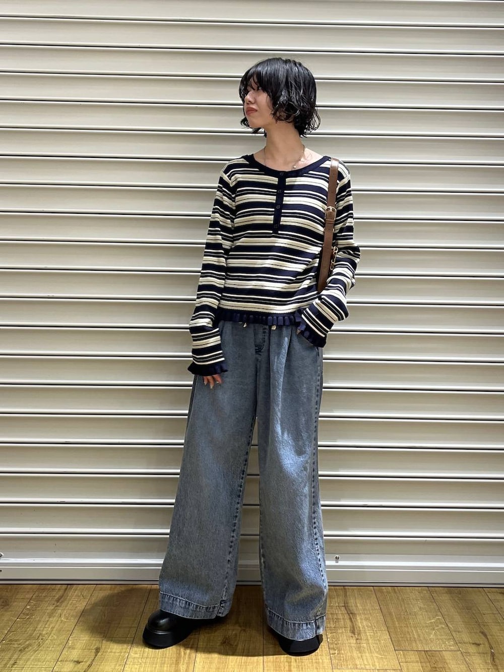 ブラック系のサンダル、ブルー系のデニムパンツ、ブラウン系のショルダーバッグを着用したレディースの冬コーディネートの3枚目の写真