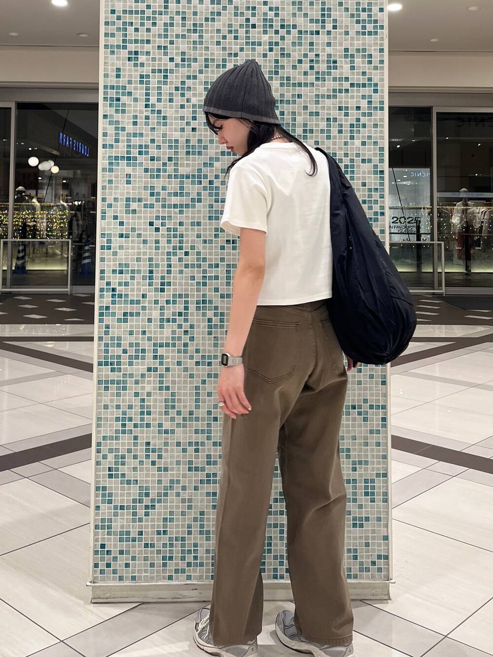 ホワイト系のTシャツ/カットソー、ブラック系のトートバッグ、ブラウン系のデニムパンツを着用したレディースの春コーディネートの3枚目の写真