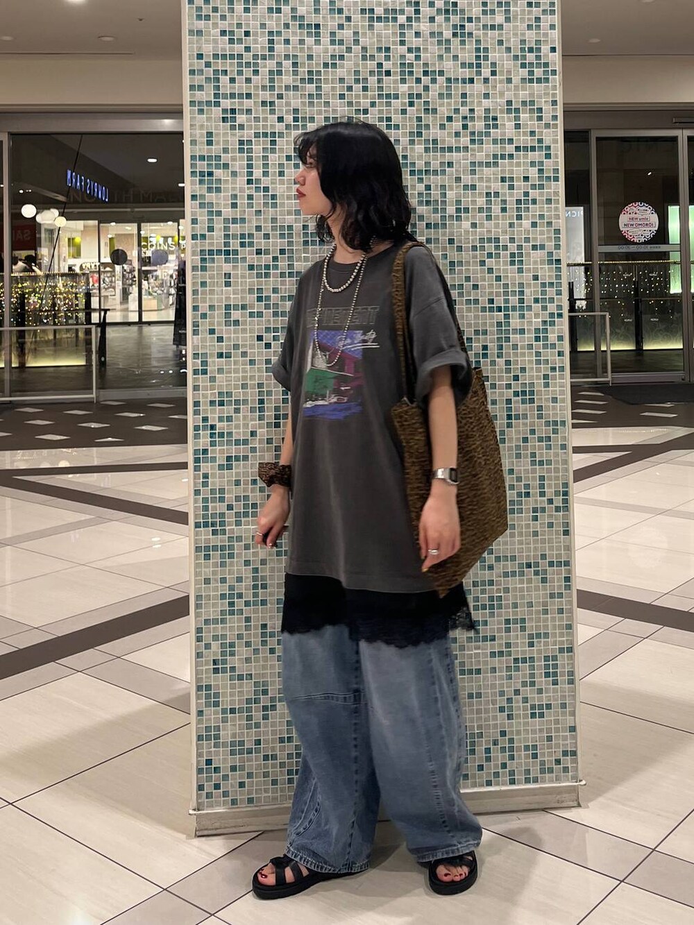 ブラック系のサンダル、その他のトートバッグ、ブルー系のデニムパンツを着用したレディースの夏コーディネートの2枚目の写真