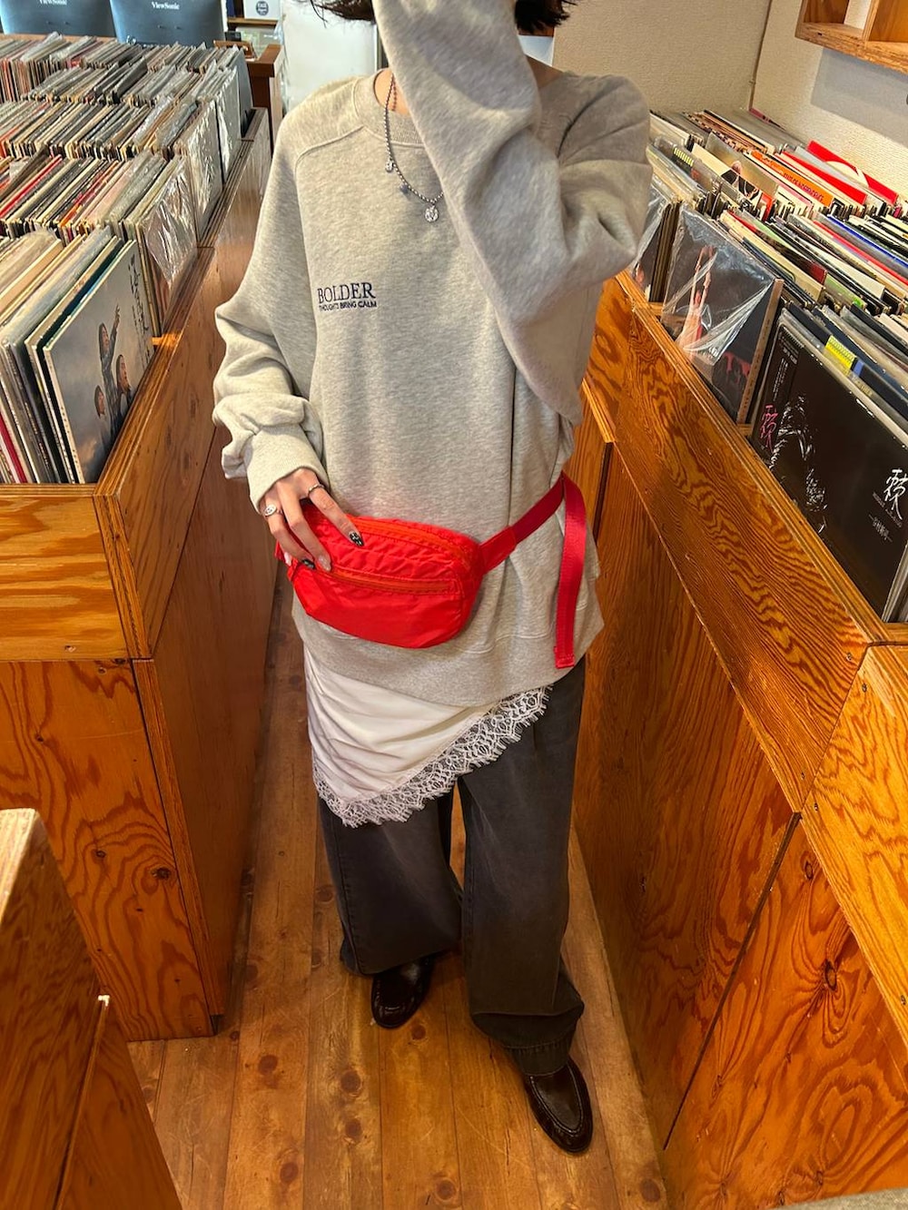 ブラック系のデニムパンツ、レッド系のボディバッグ/ウエストポーチ、グレー系のスウェットを着用したレディースの冬コーディネートの4枚目の写真
