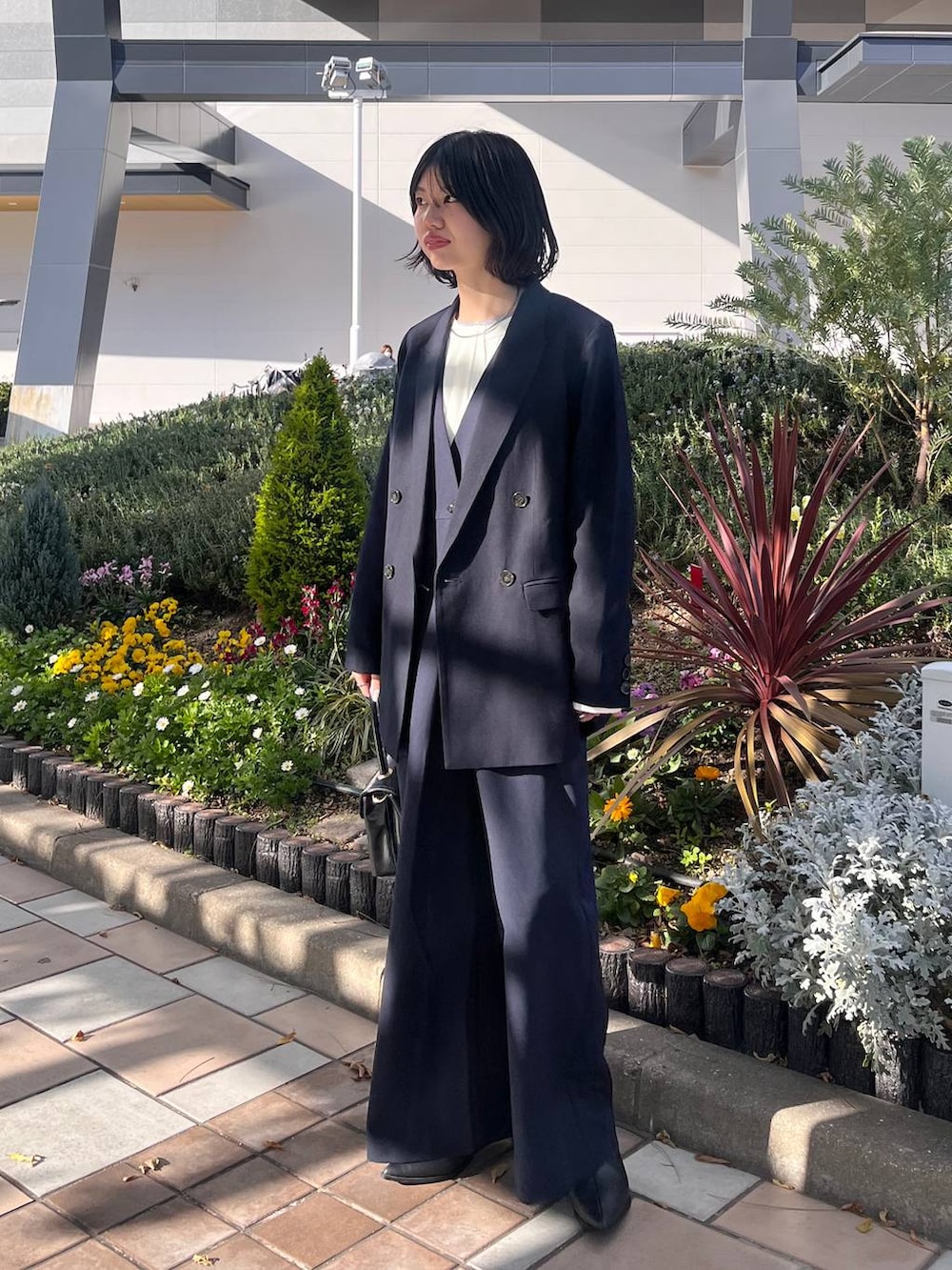 ブラック系のボストンバッグ、ブラック系のブーツ、ホワイト系のシャツ/ブラウスを着用したレディースの冬コーディネートの2枚目の写真