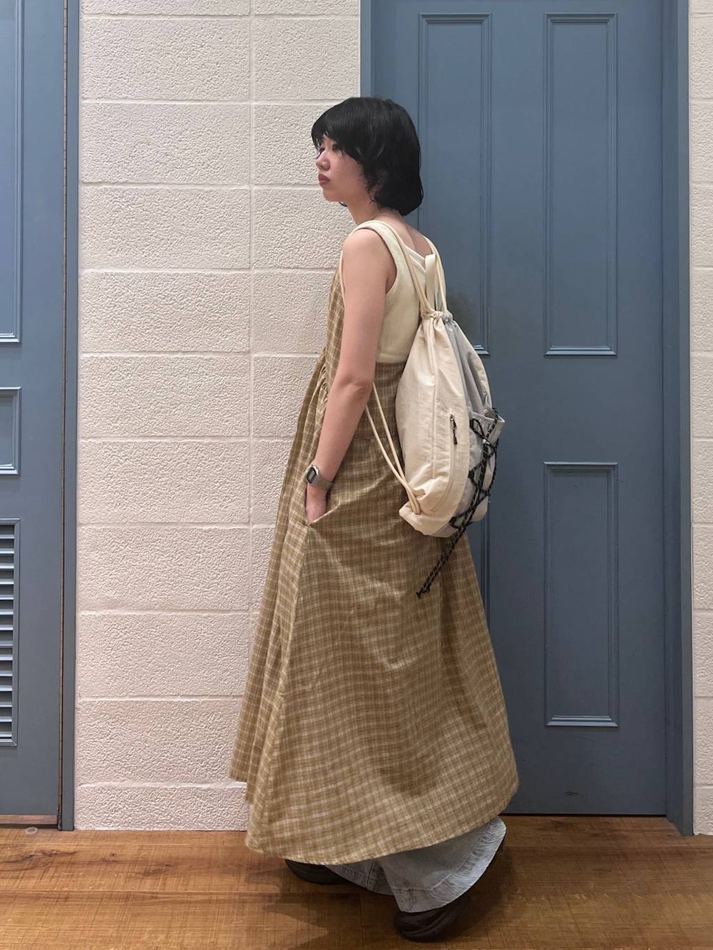 ブルー系のデニムパンツ、ホワイト系のタンクトップ、イエロー系のワンピースを着用したレディースの春コーディネートの2枚目の写真