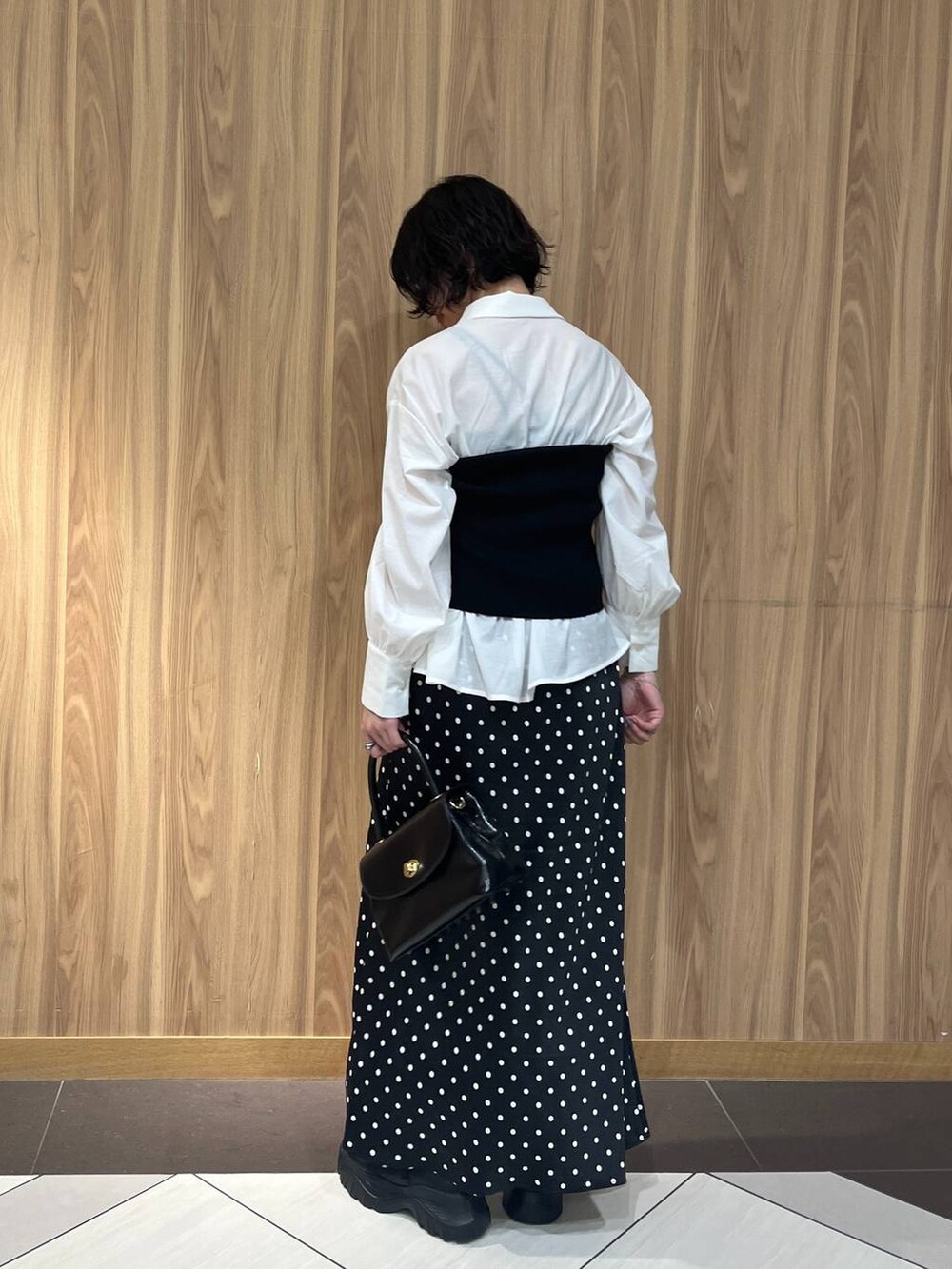 ブラック系のスニーカー、ブラック系のスカート、ブラック系のボストンバッグを着用したレディースの秋コーディネートの3枚目の写真