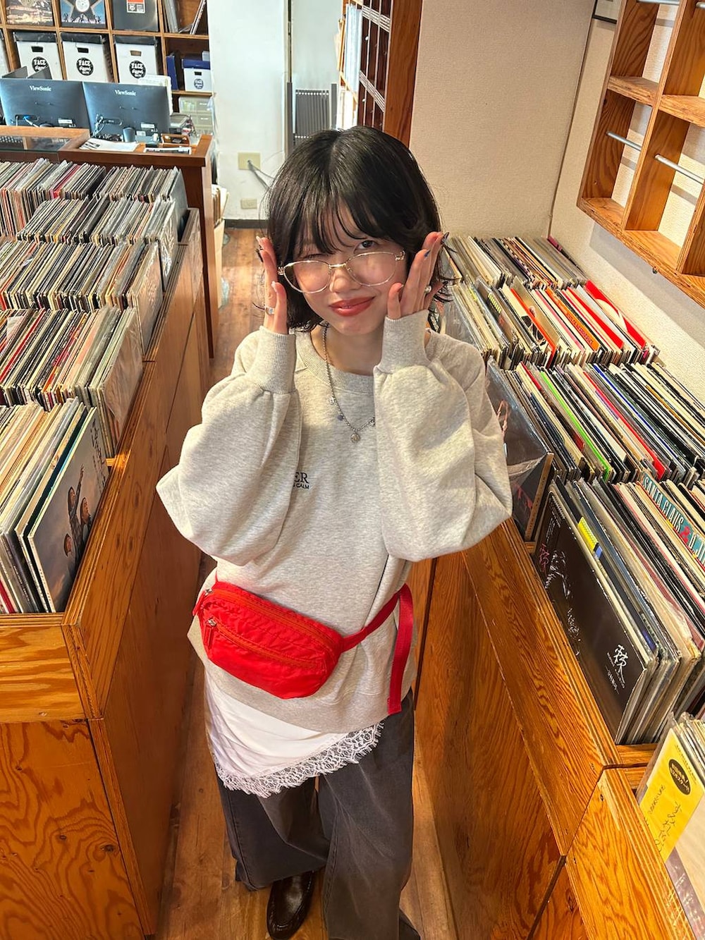 ブラック系のデニムパンツ、レッド系のボディバッグ/ウエストポーチ、グレー系のスウェットを着用したレディースの冬コーディネートの3枚目の写真