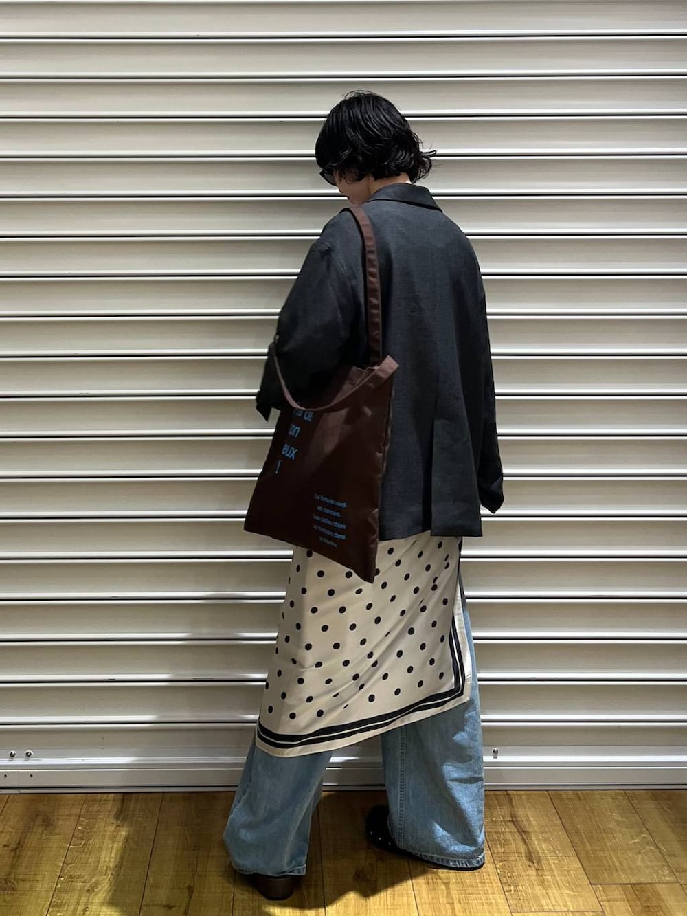 グレー系のテーラードジャケット、ブルー系のデニムパンツ、ブラック系のサンダルを着用したレディースの春コーディネートの3枚目の写真