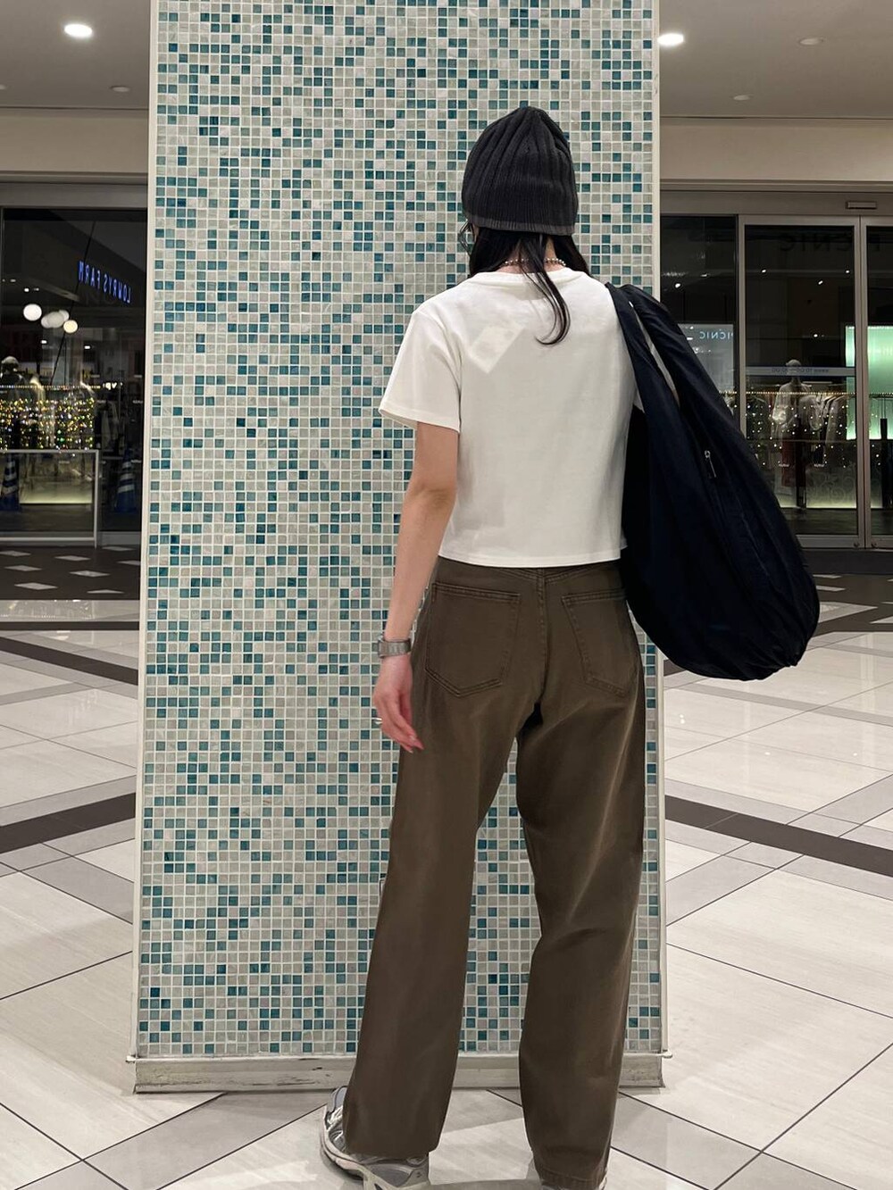 ホワイト系のTシャツ/カットソー、ブラック系のトートバッグ、ブラウン系のデニムパンツを着用したレディースの春コーディネートの2枚目の写真