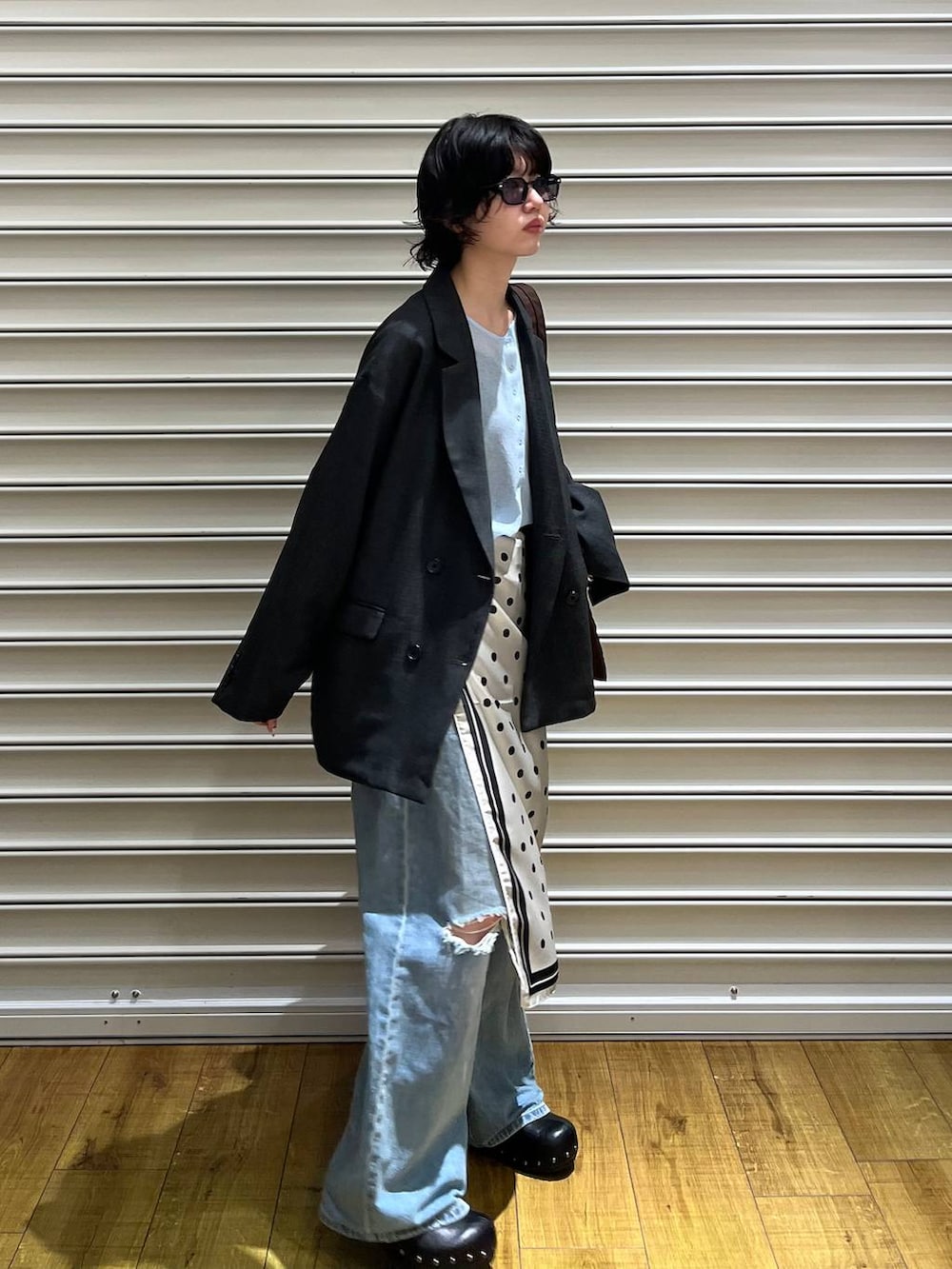 グレー系のテーラードジャケット、ブルー系のデニムパンツ、ブラック系のサンダルを着用したレディースの春コーディネートの5枚目の写真