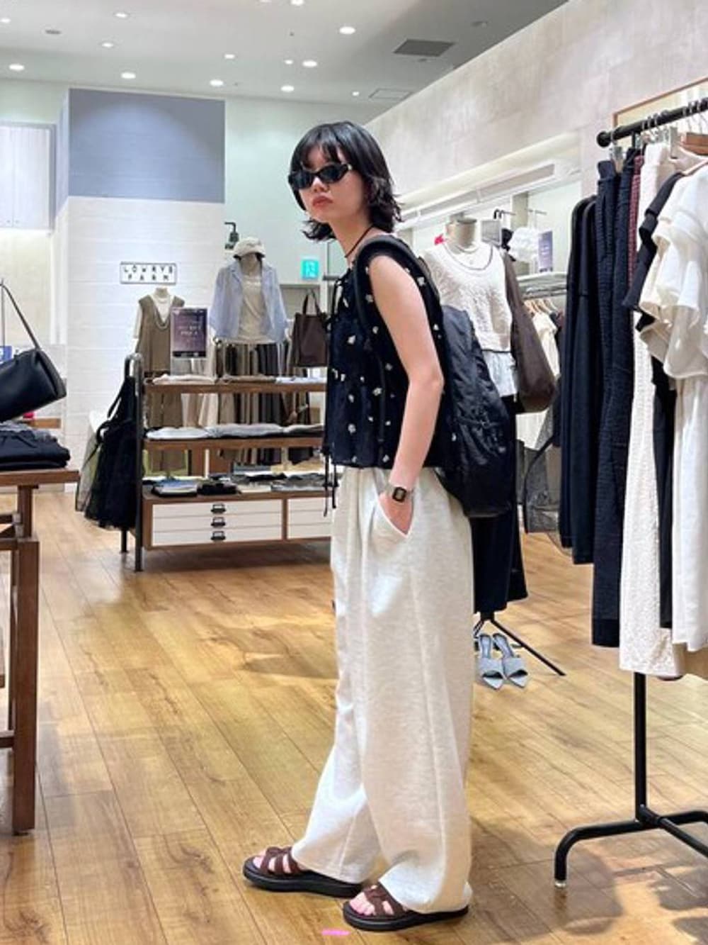 グレー系のスウェットパンツ、ブラウン系のサンダル、ブラック系のバックパック/リュックを着用したレディースの夏コーディネートの2枚目の写真