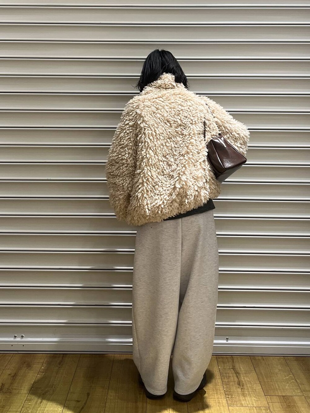 グレー系のスウェットパンツ、ブラウン系のボストンバッグ、ホワイト系のブルゾンを着用したレディースの冬コーディネートの3枚目の写真