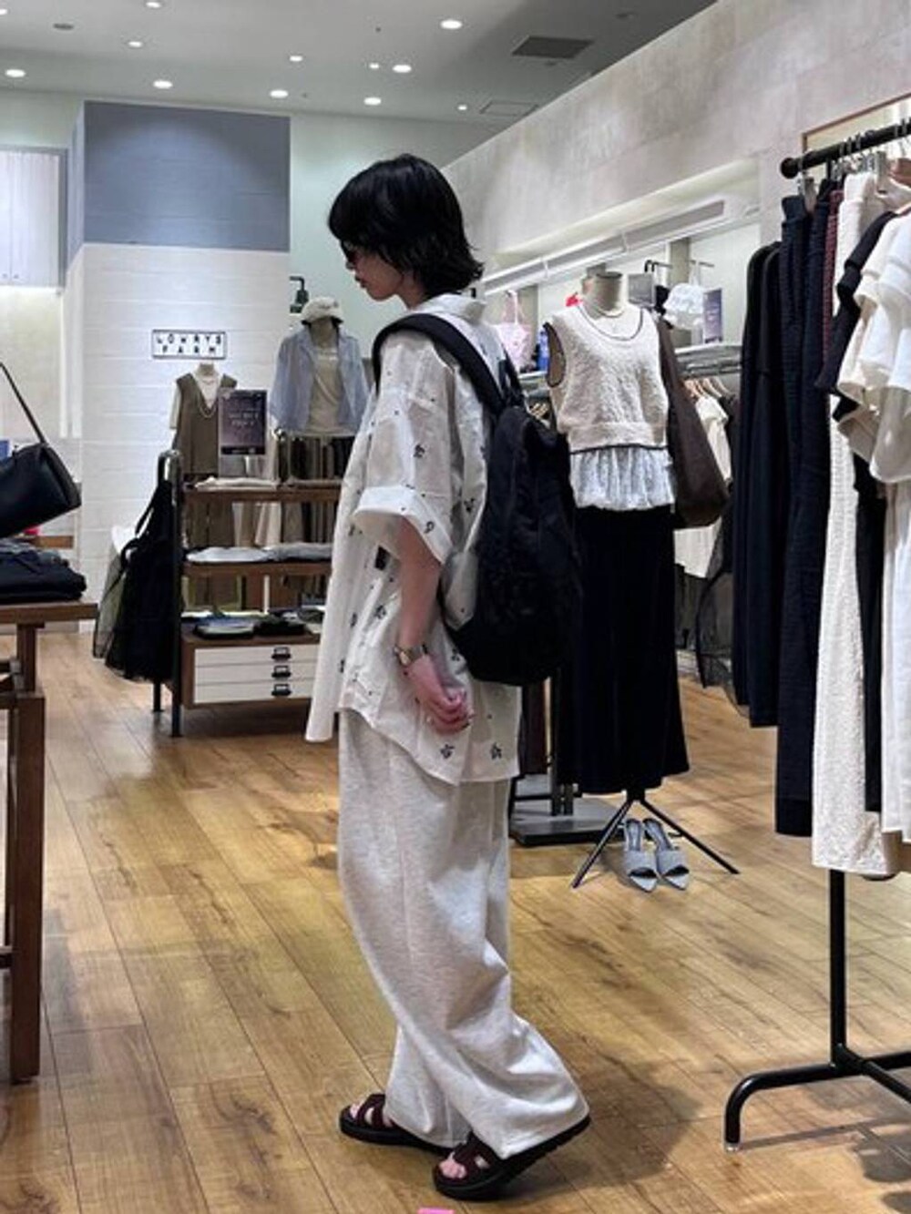 グレー系のスウェットパンツ、ブラウン系のサンダル、ブラック系のキャミソールを着用したレディースの夏コーディネートの2枚目の写真