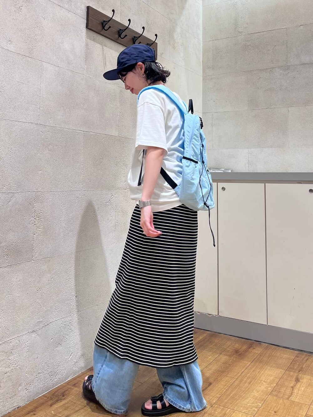 ブルー系のデニムパンツ、ブラック系のサンダル、ホワイト系のTシャツ/カットソーを着用したレディースの夏コーディネートの3枚目の写真